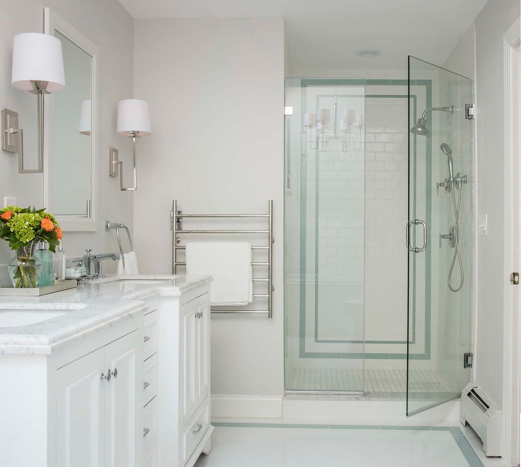 Bathroom with white and gray color scheme, featuring a glass shower, double sink vanity, and towel warmer.
