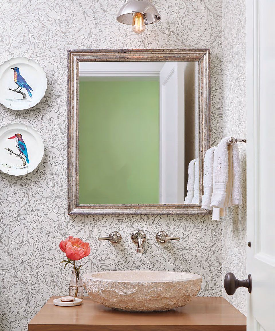 Bathroom with stone sink, mirror, floral wallpaper, and decorative plates.