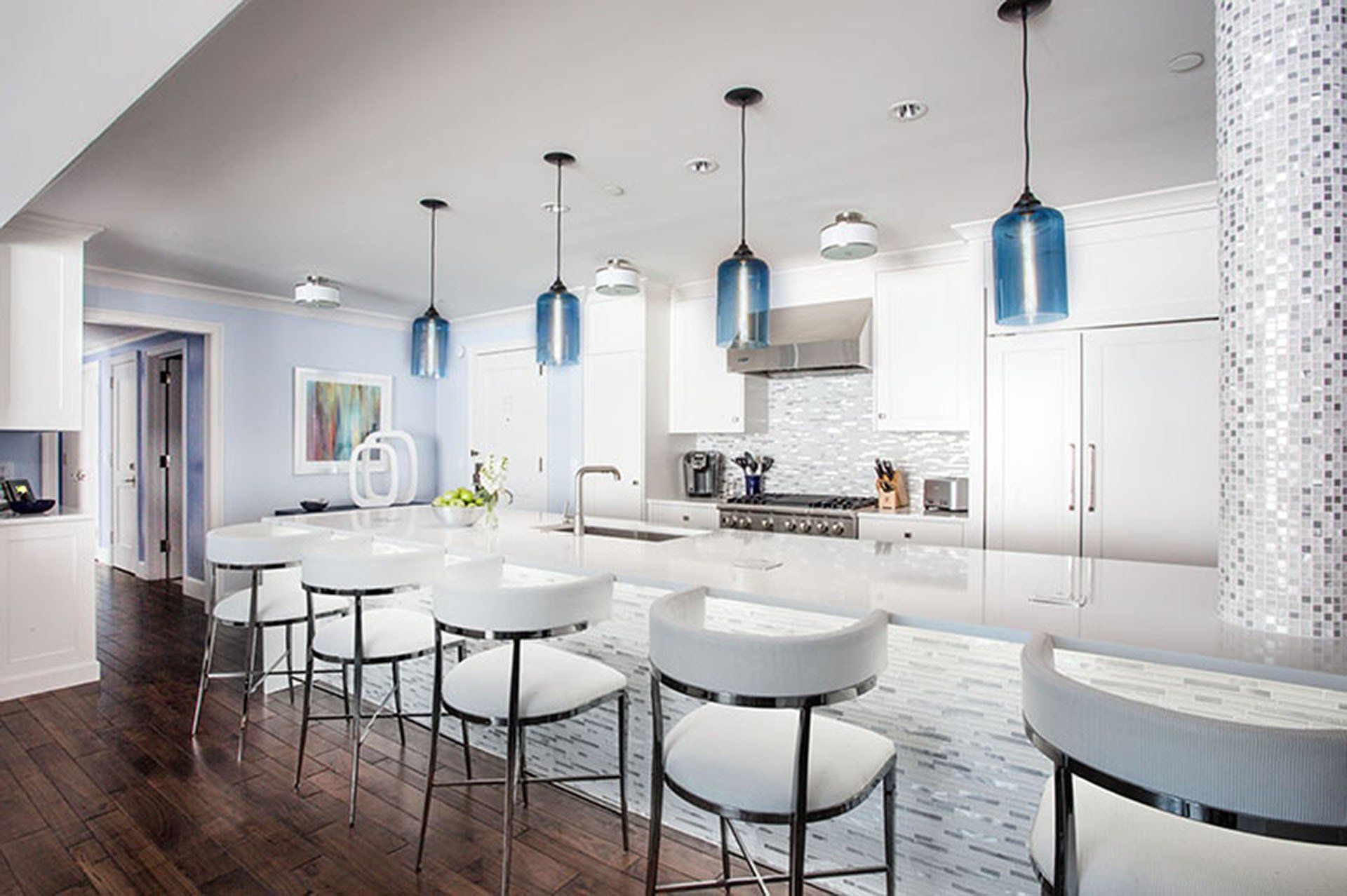 Modern kitchen with white cabinets, blue pendant lights, and island with barstools.