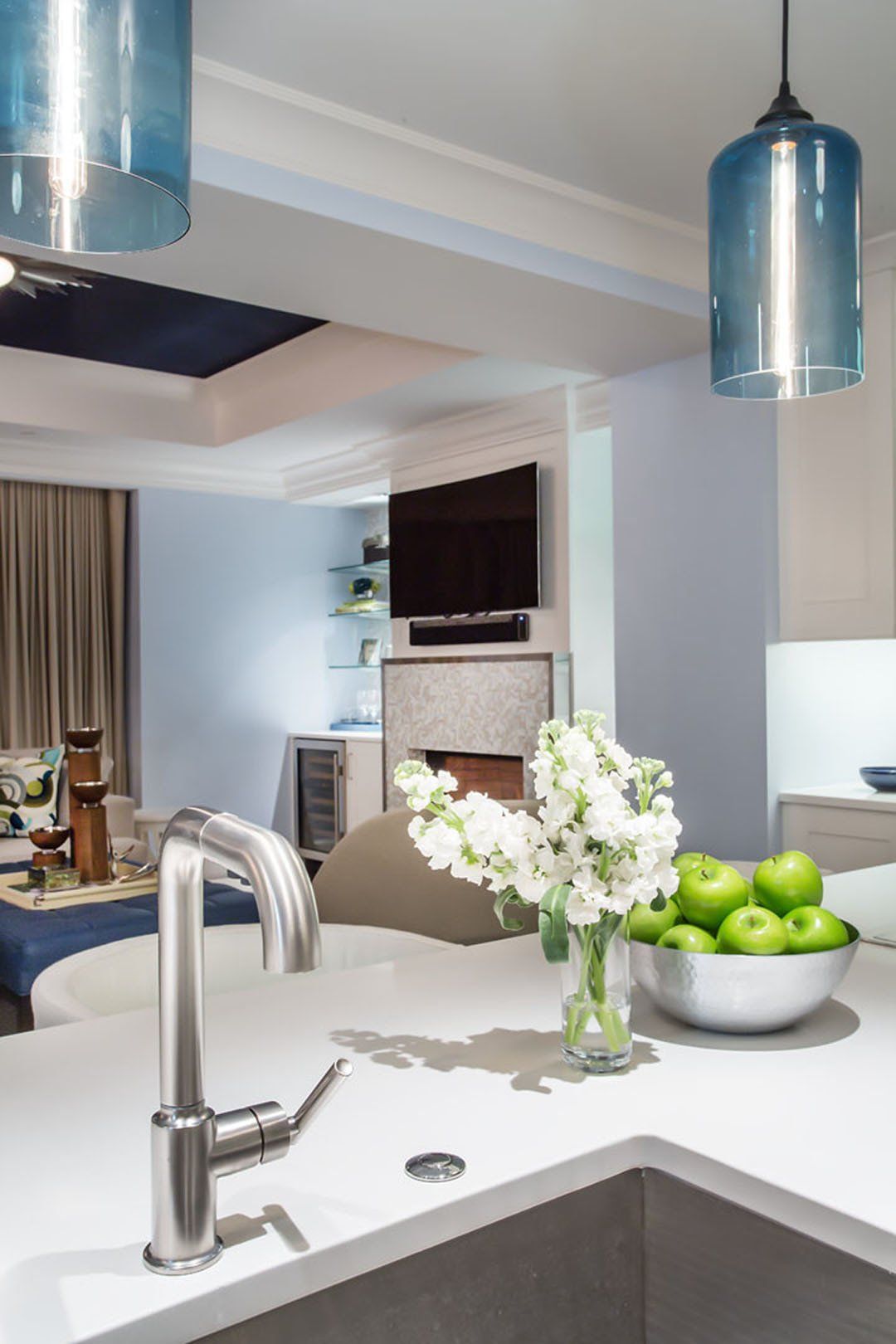 Kitchen island with faucet, sink, and flowers; blue pendant lights.