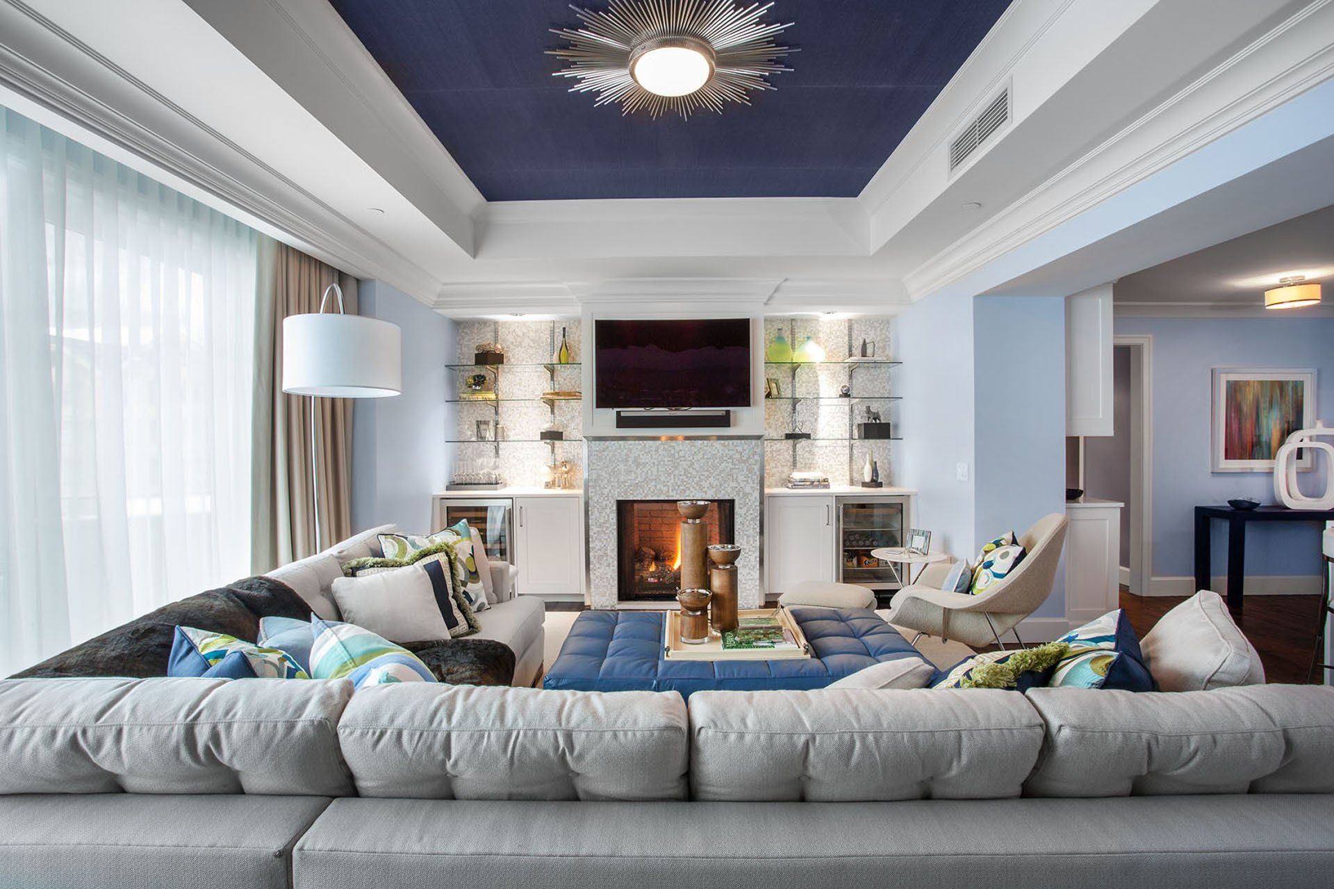 Spacious living room with blue ceiling, fireplace, sectional sofa, and light blue walls.