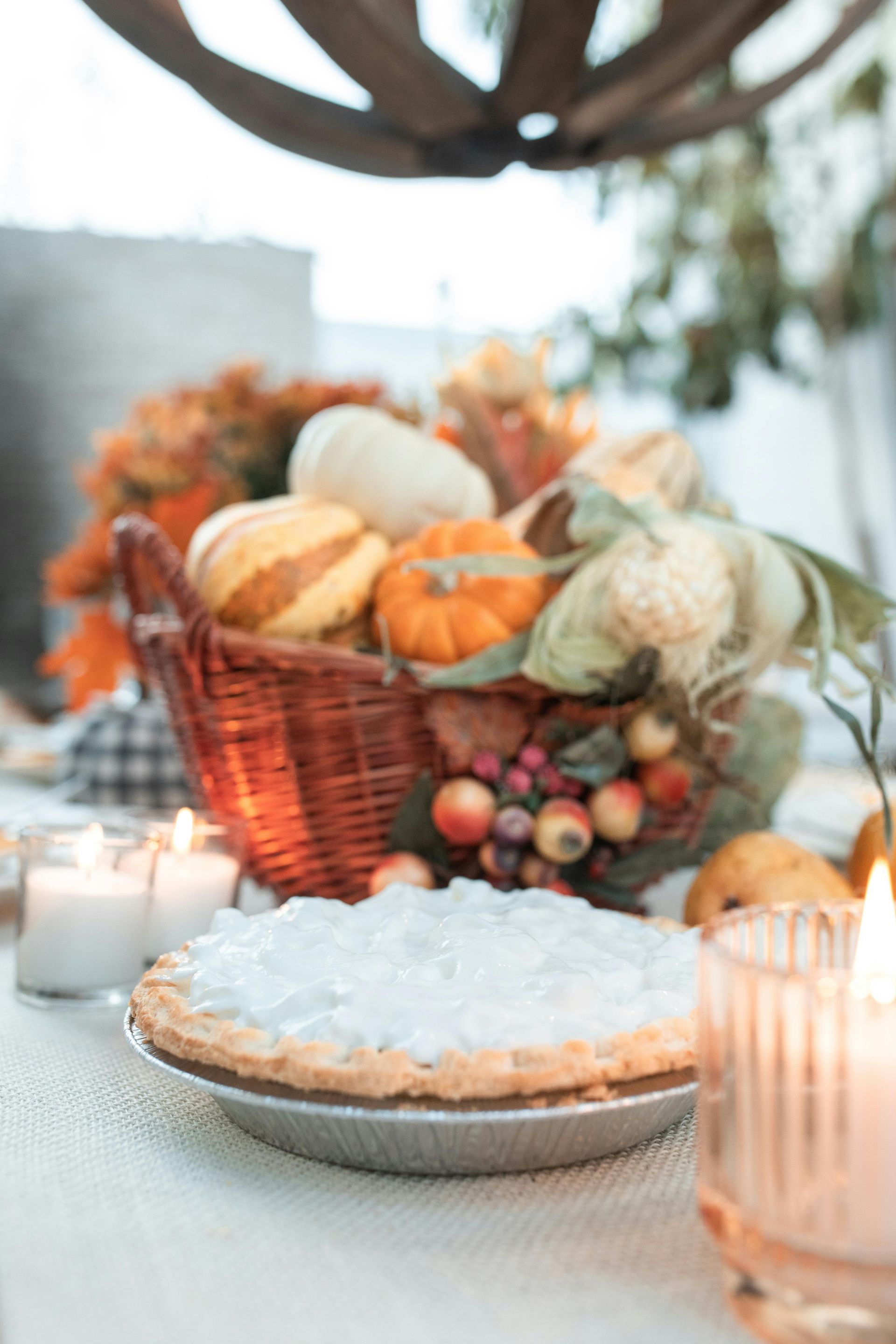 Coconut pie, pumpkins, corn, and candles on a table set for fall.