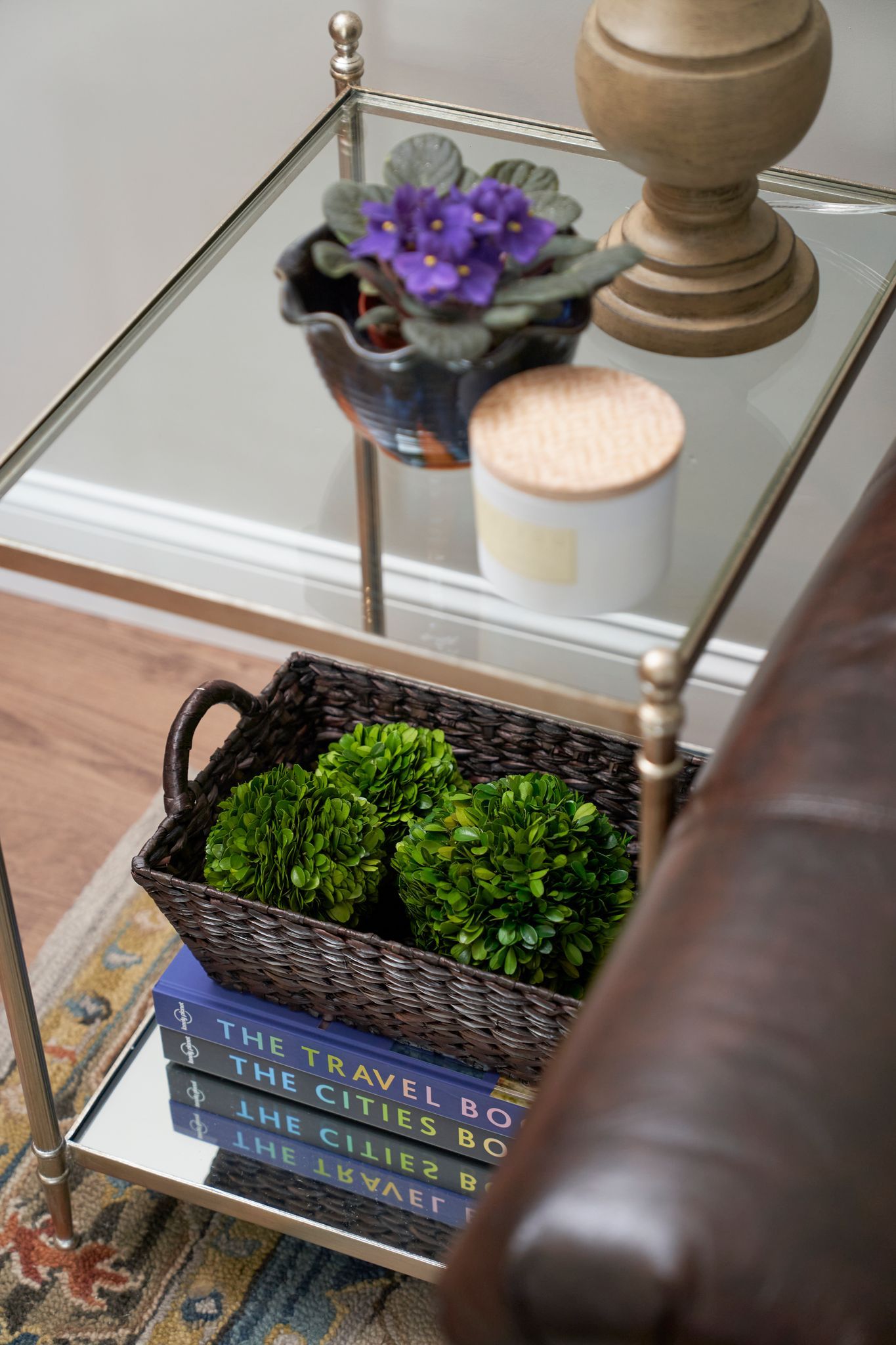 Glass side table with plants, books, and decorative items.