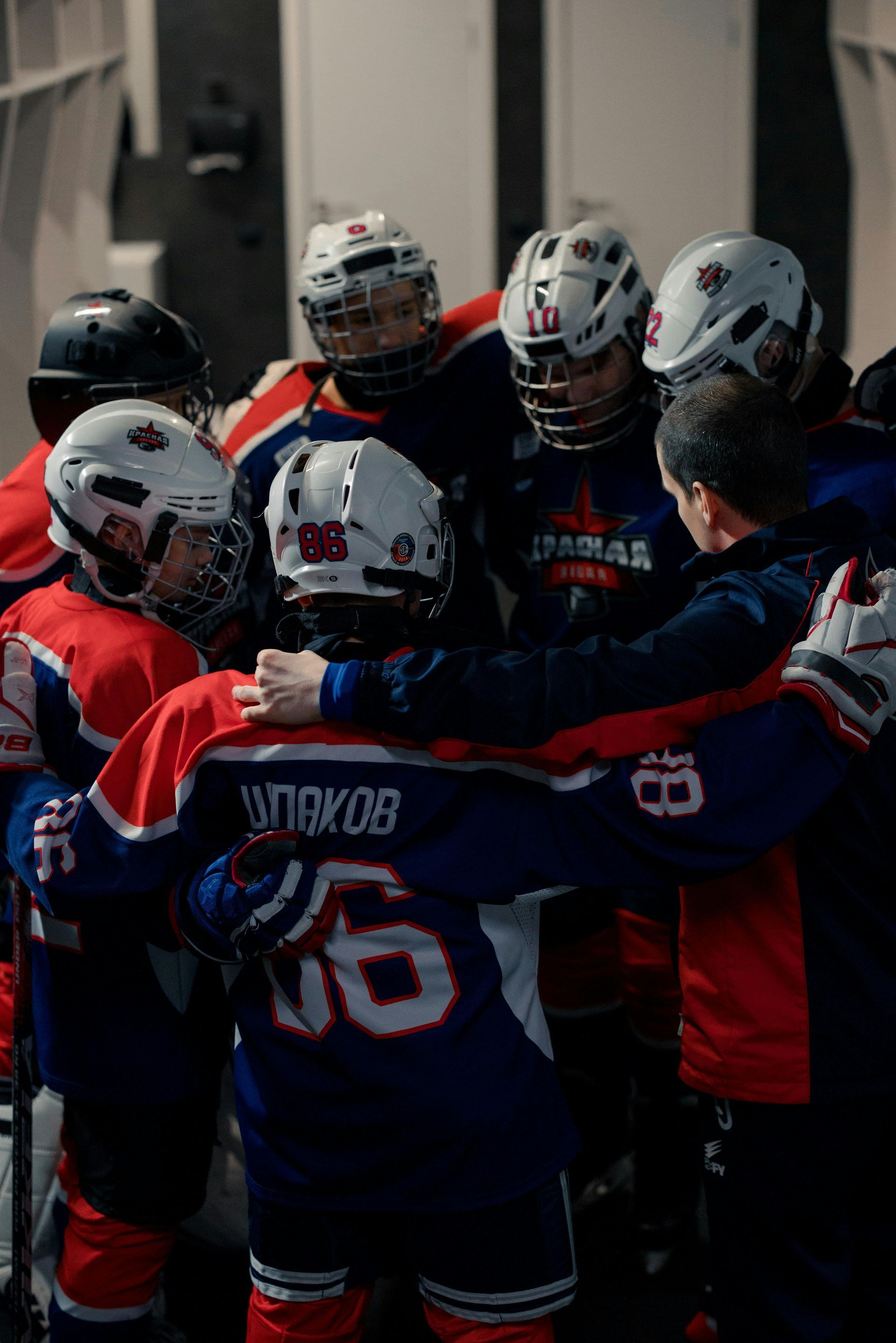 Hockey team huddled together, wearing red and blue jerseys, preparing for a game.