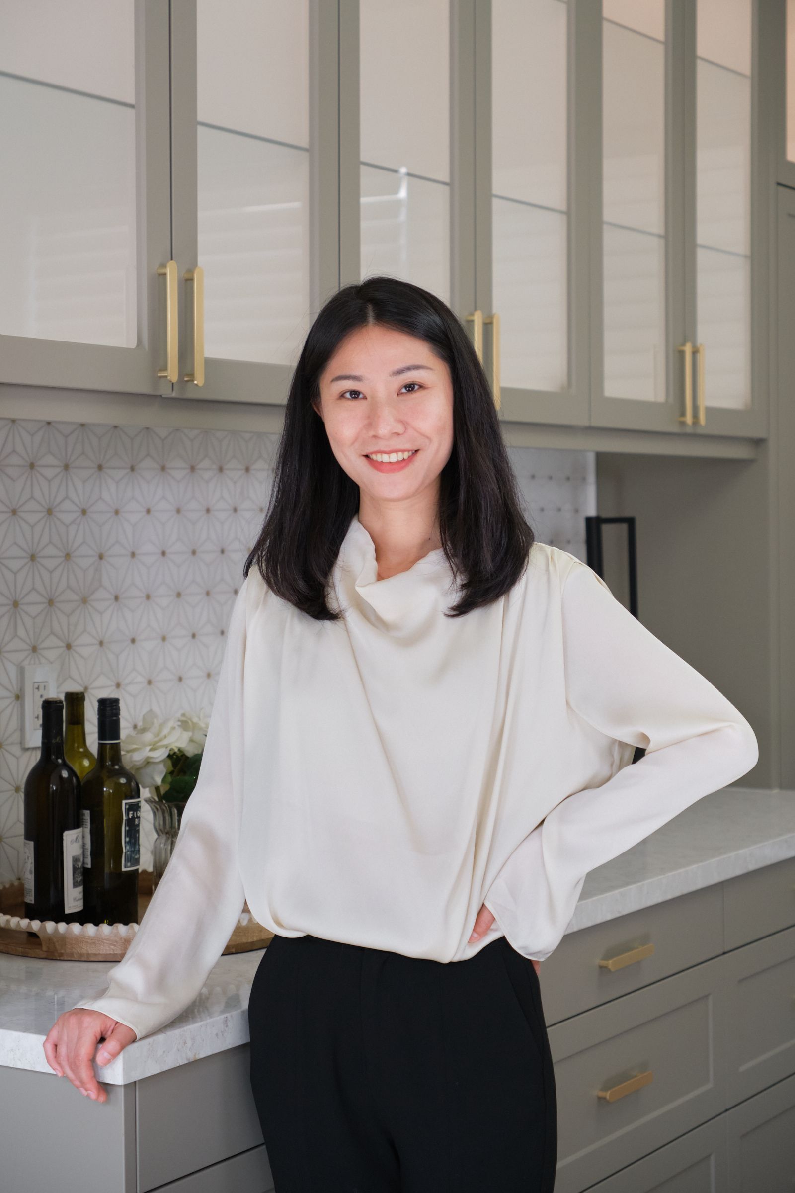 A woman is standing in a kitchen leaning on a counter.