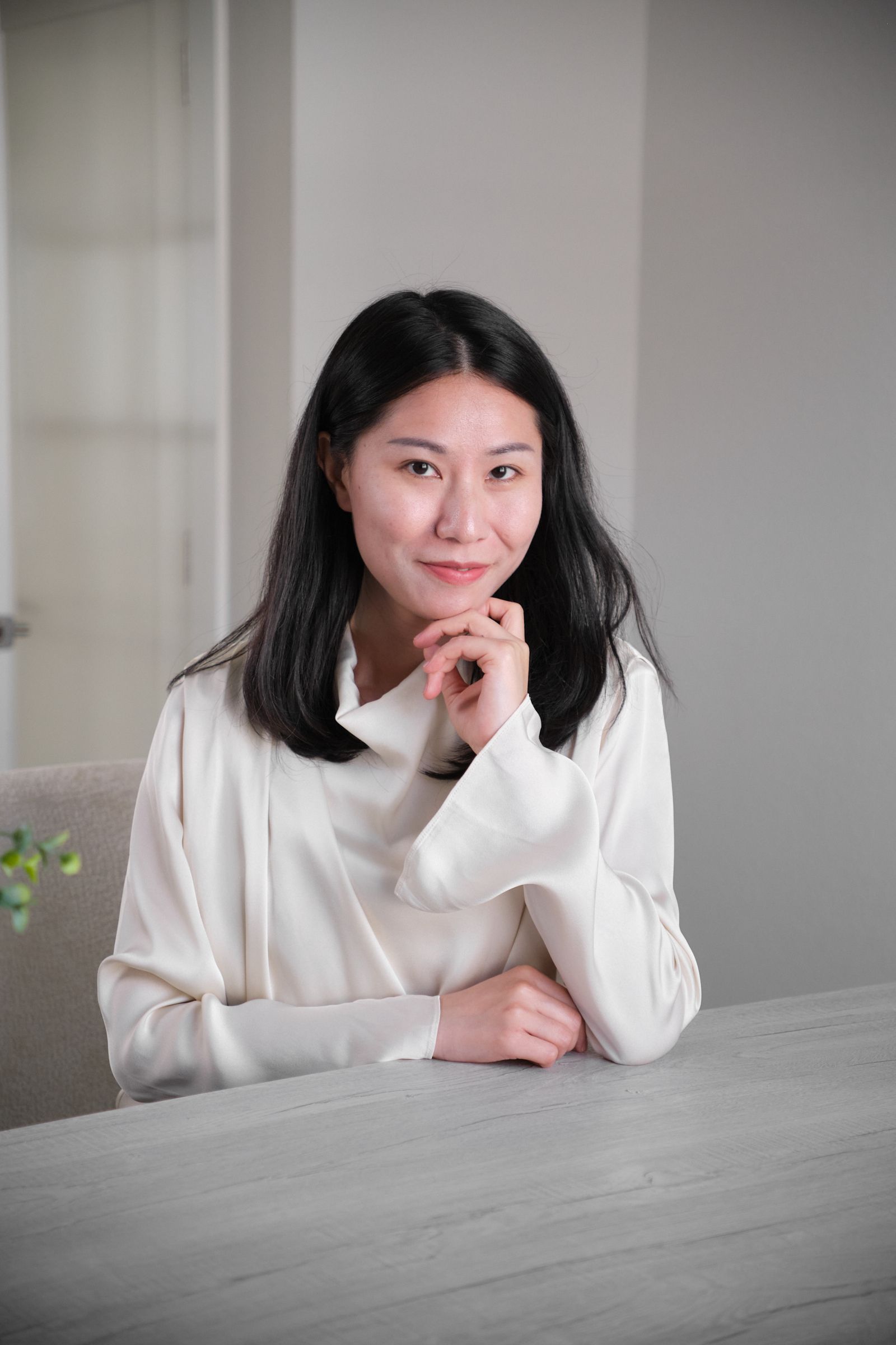 A woman is sitting at a table with her hand on her chin.