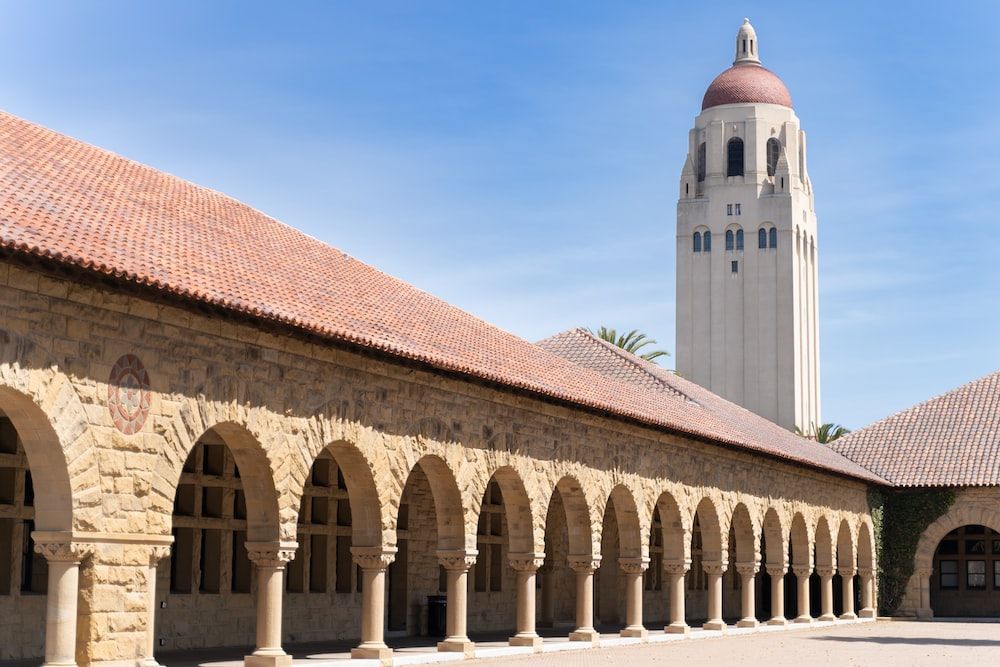 A large building with arches and a tower in the background.
