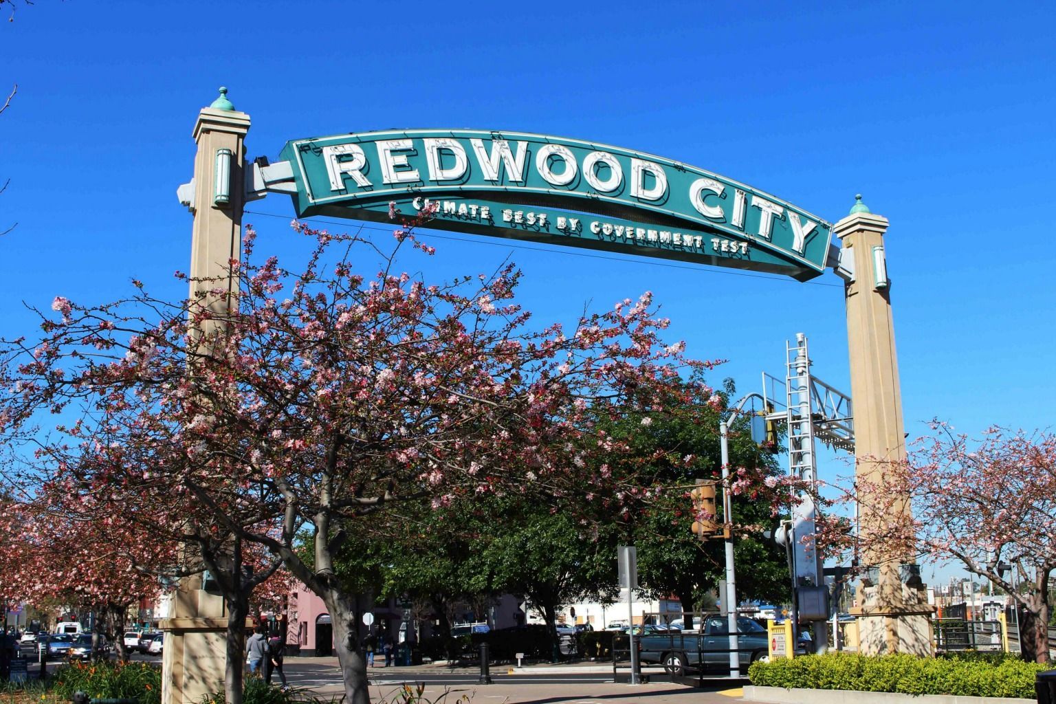 A sign for redwood city is surrounded by trees and flowers