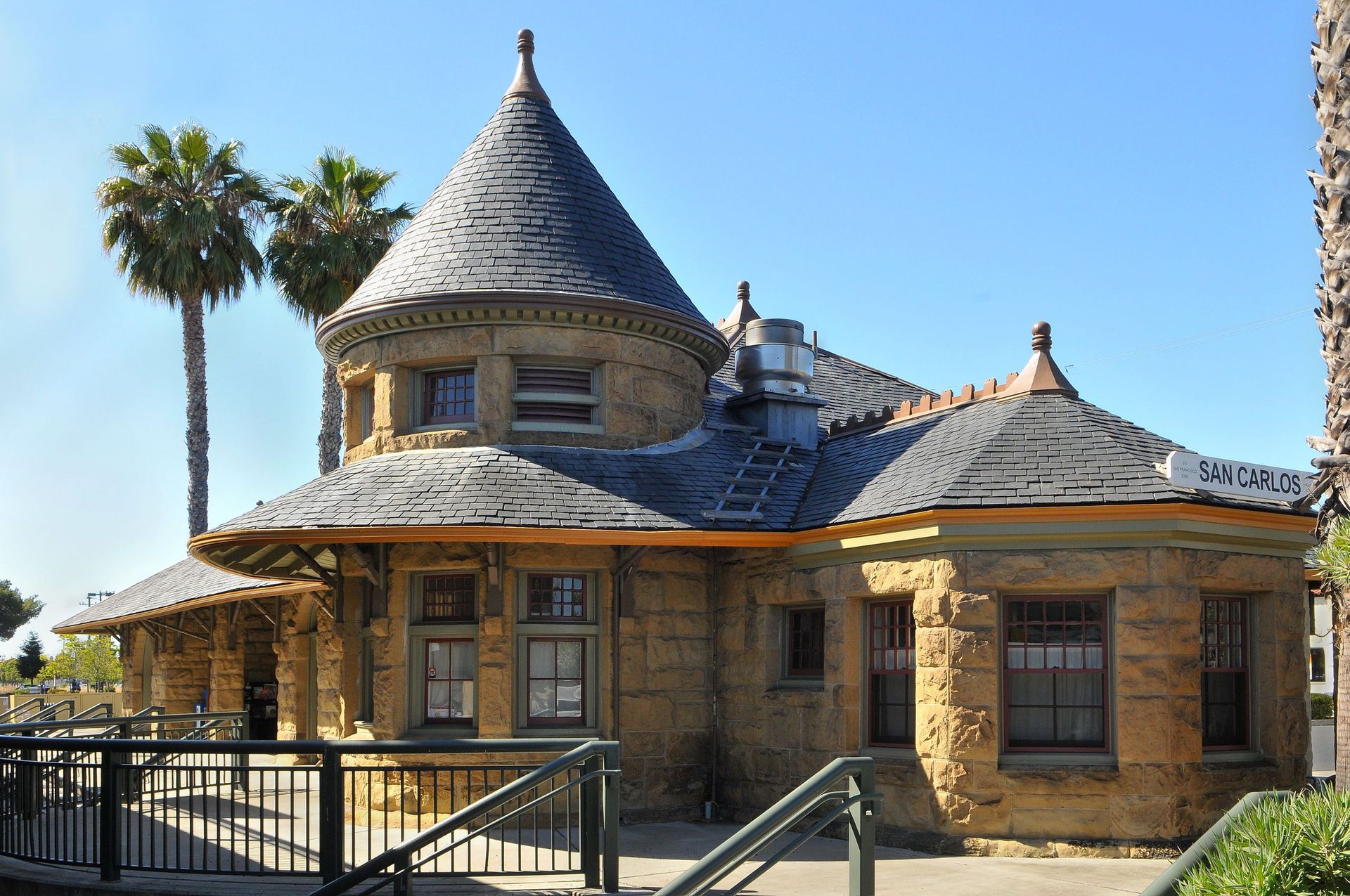 A large stone building with a conical roof and palm trees in the background