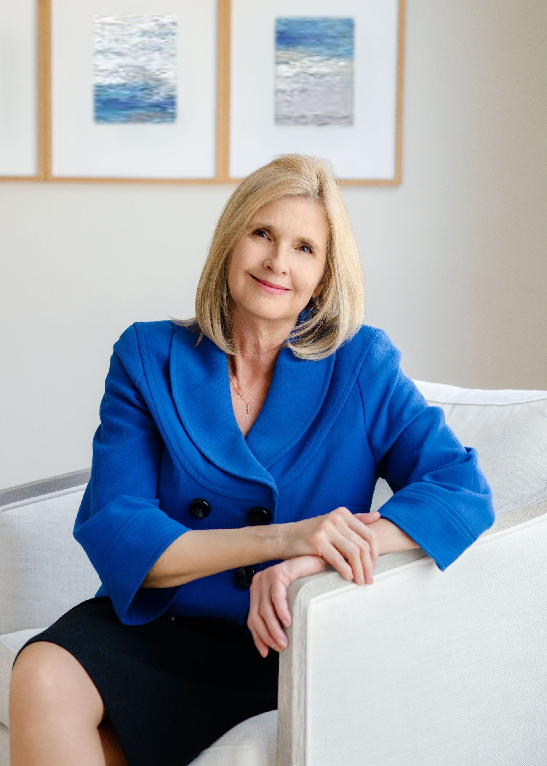 A woman in a blue jacket is sitting on a couch.