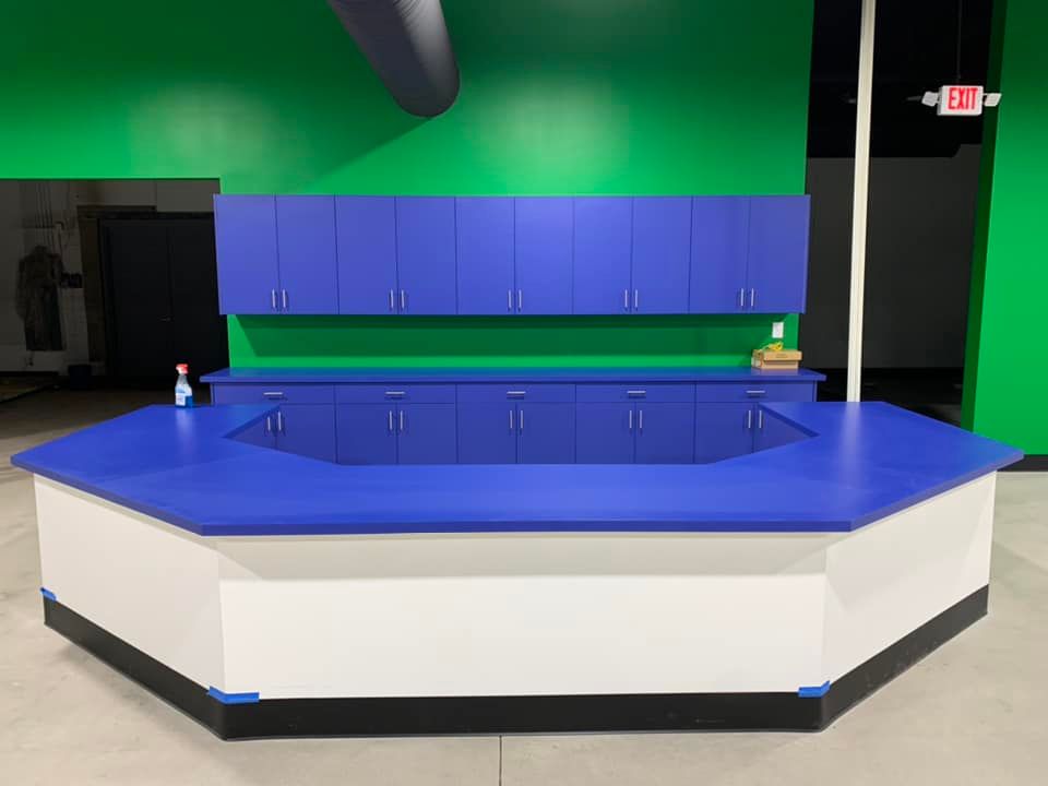 An octagonal blue countertop and cabinetry with white and black trim against a green wall.