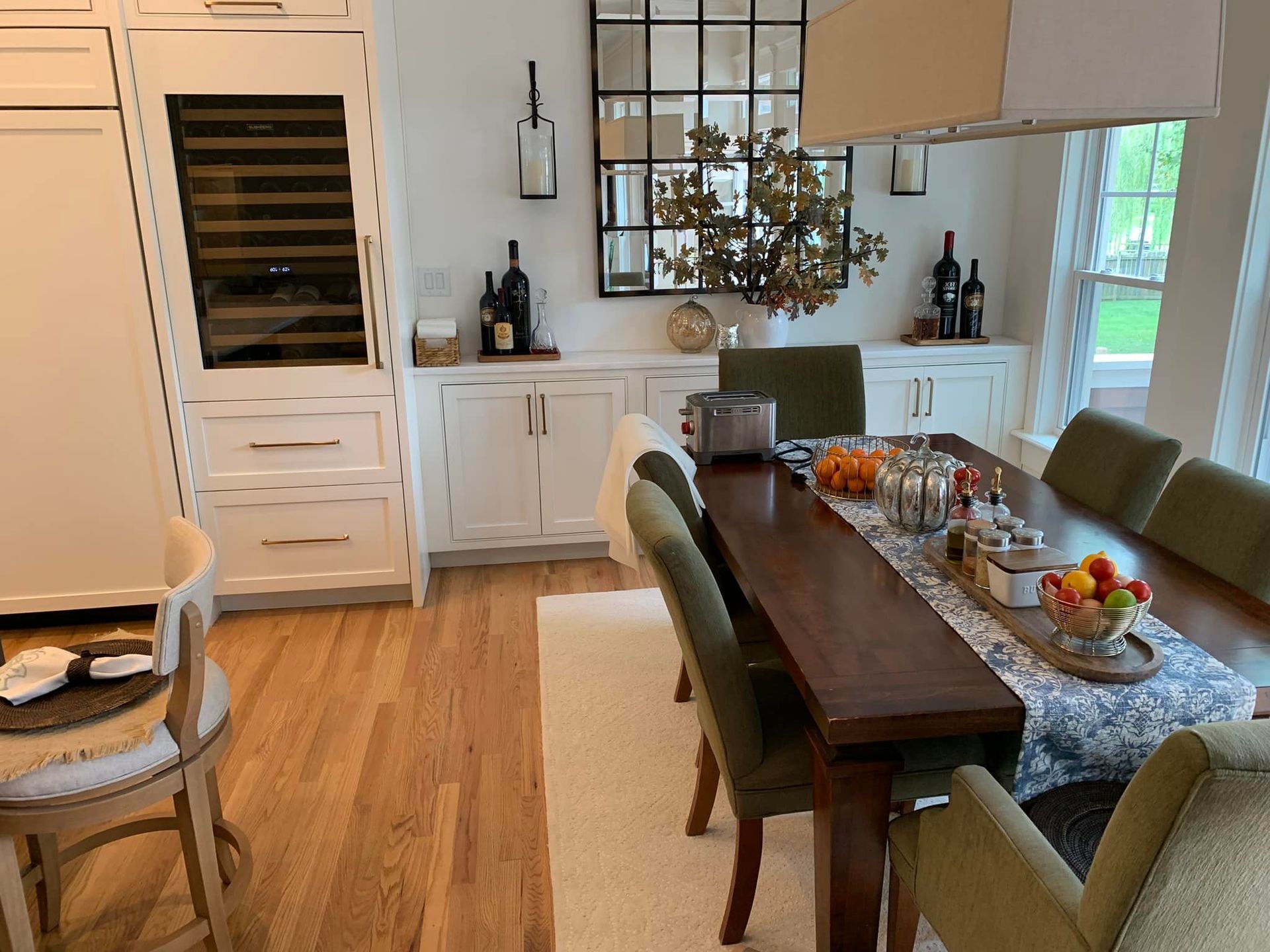 A dining room with a long wooden table set for a meal, flanked by green velvet chairs.