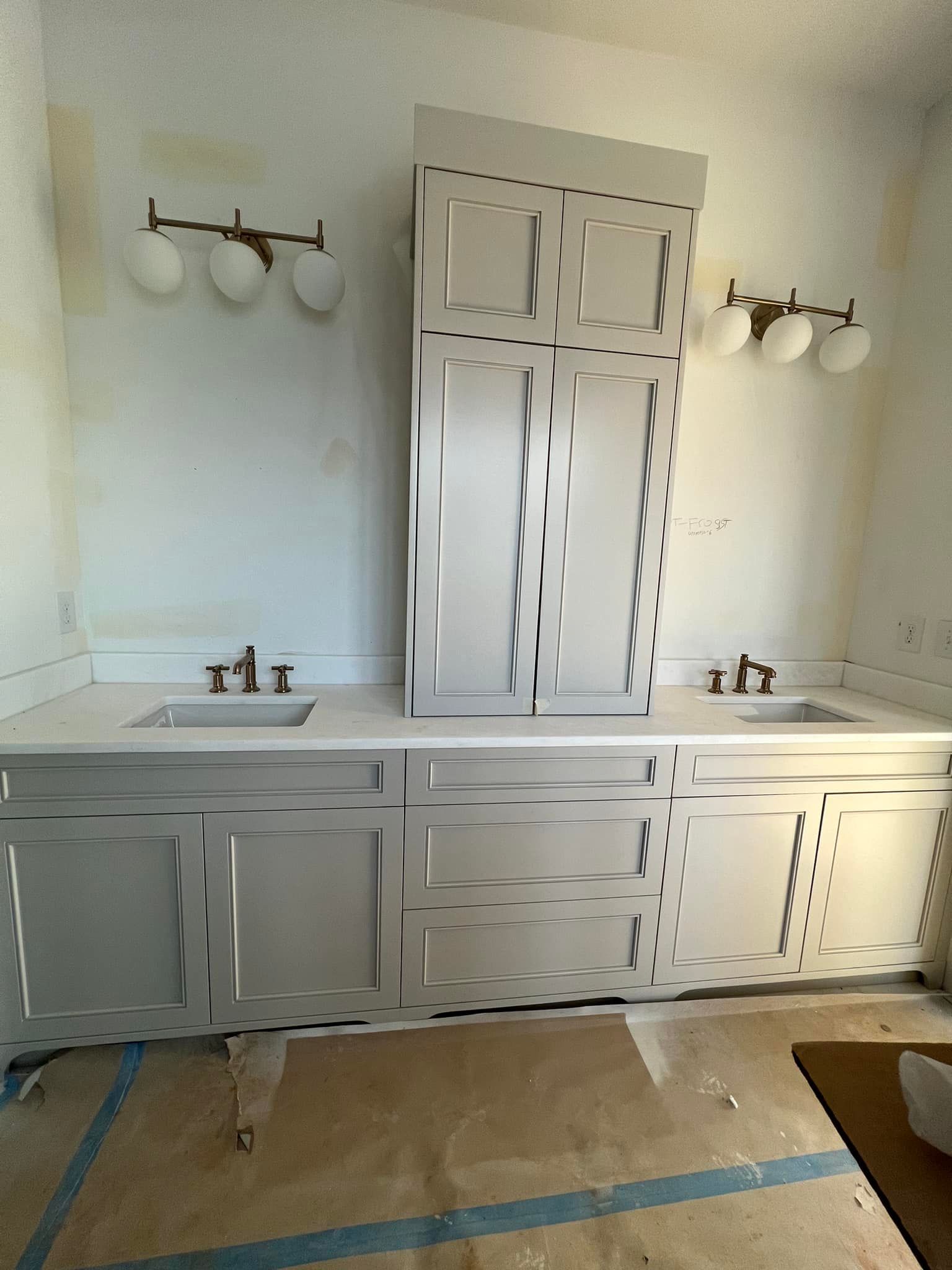 Bathroom with light gray vanity cabinets, a tall matching storage cabinet, two sinks