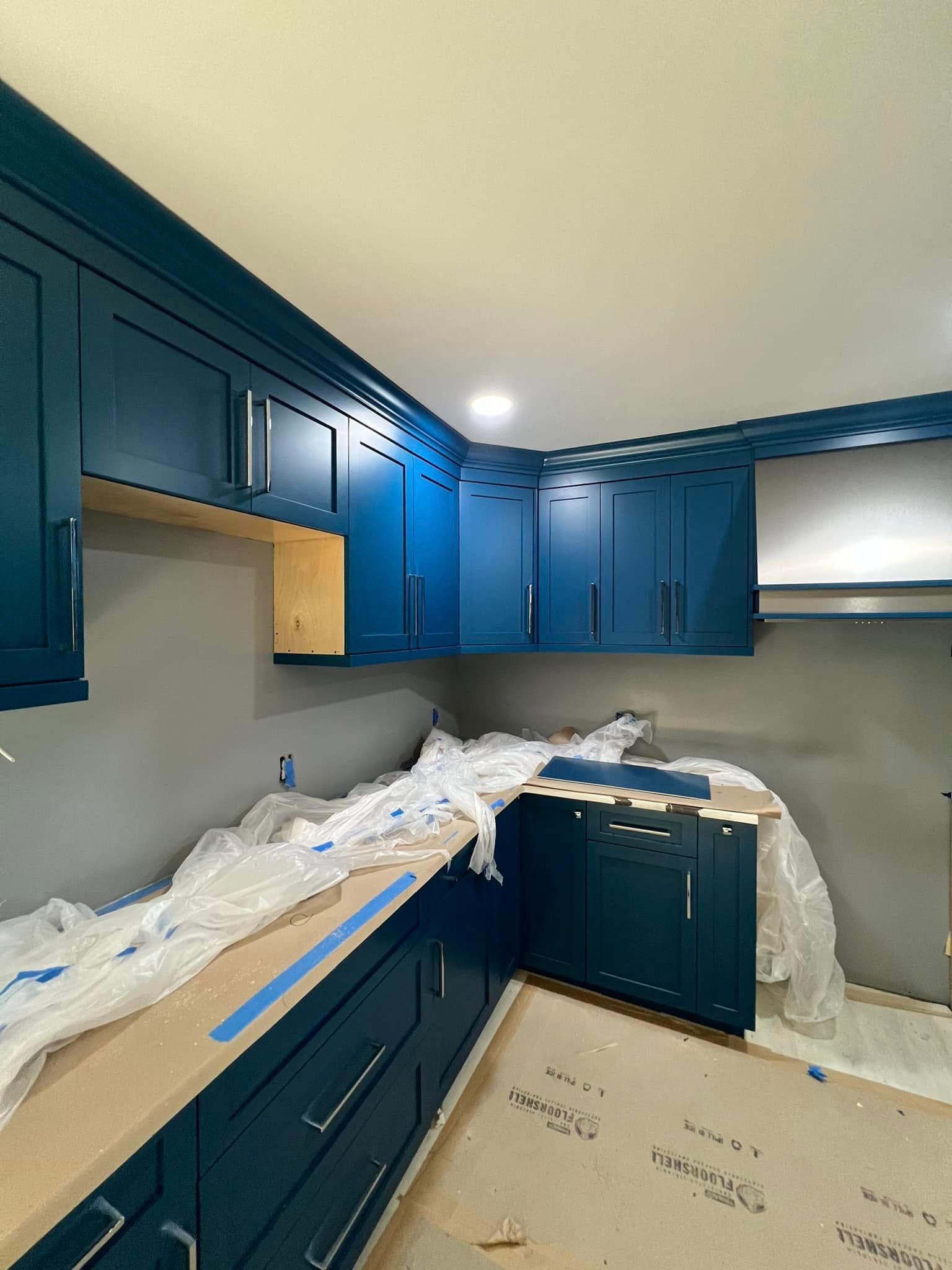 Blue kitchen cabinets and countertops with unfinished walls, under construction.