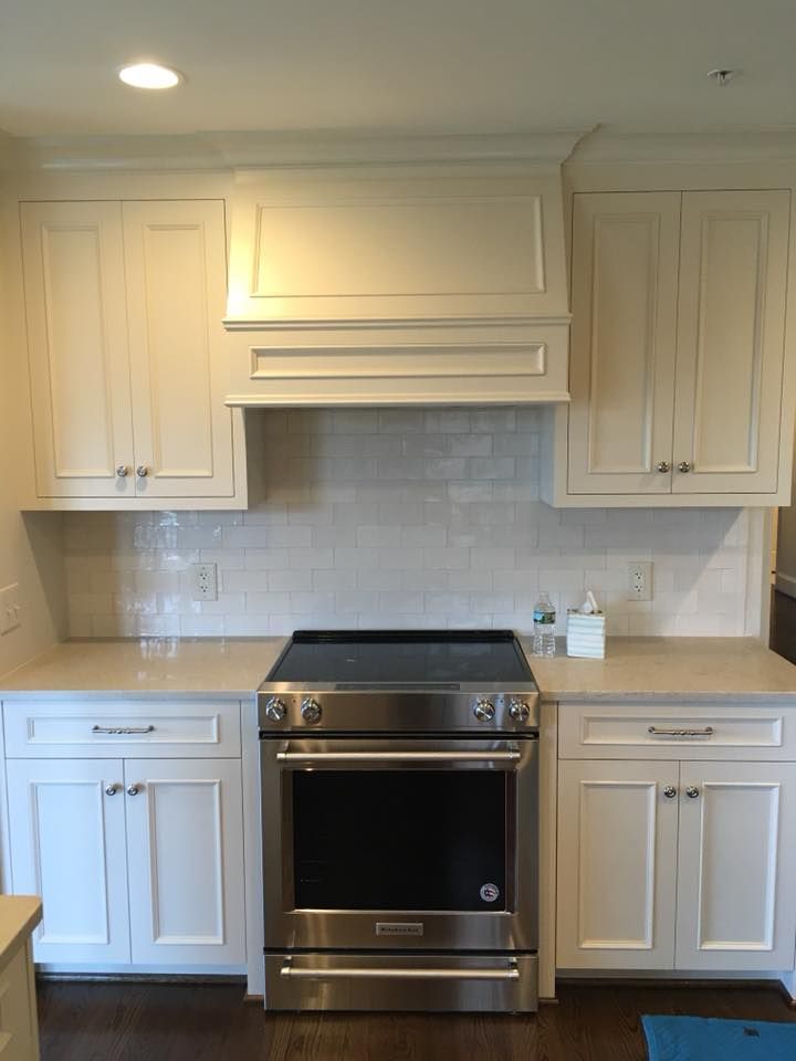 Cream-colored kitchen cabinets surround a stainless steel range.