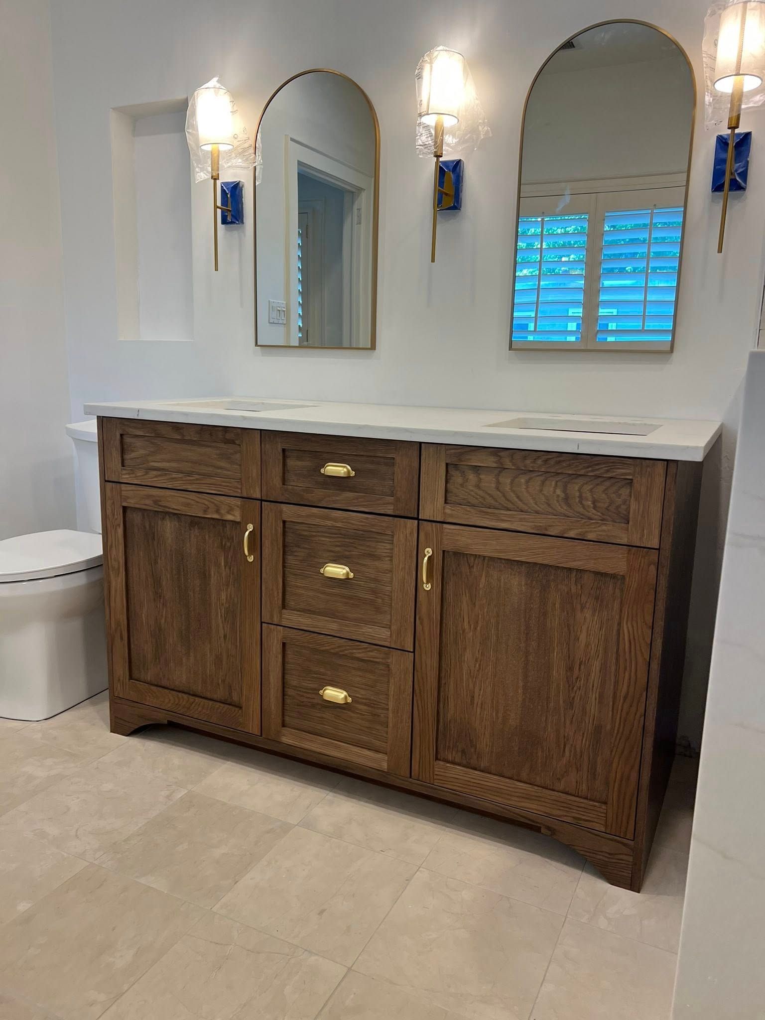 Bathroom vanity with brown wooden cabinets, a white countertop, and gold hardware.
