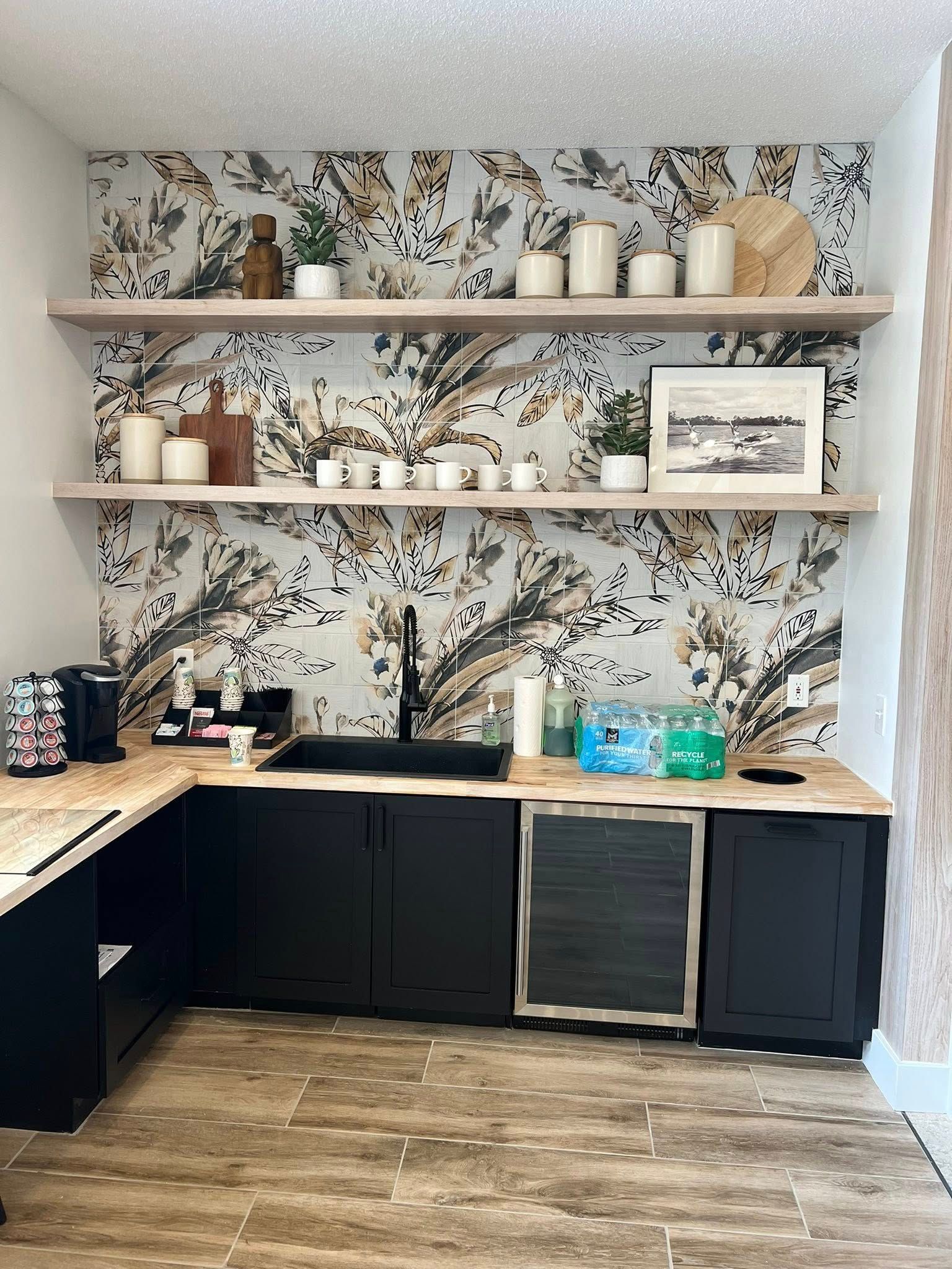 Black cabinets and countertops with an under-counter beverage cooler, black sink and faucet.