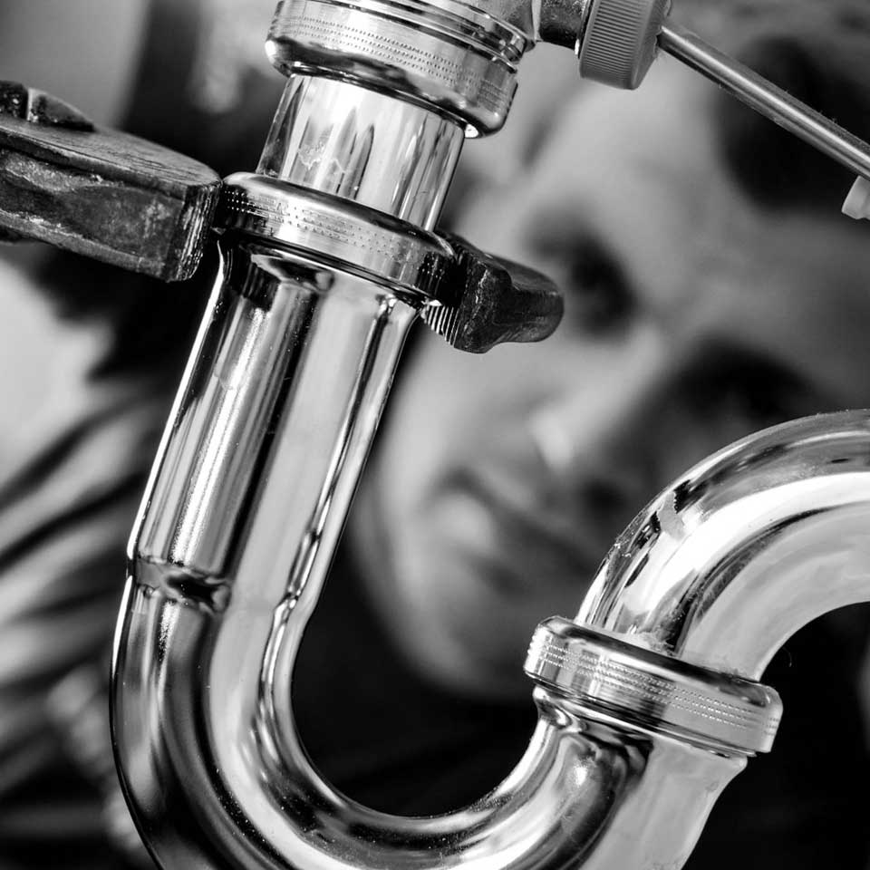 Close-up of a man looking at a silver plumbing pipe