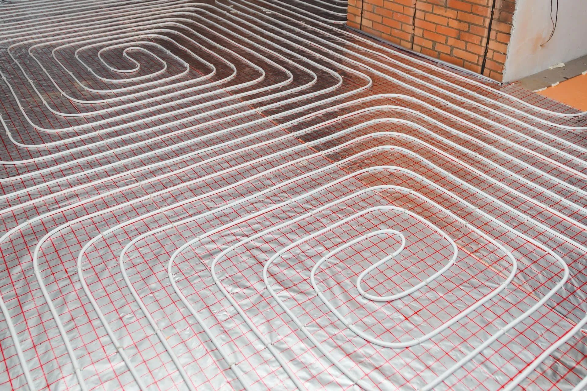 Close-up of a floor with heating pipes arranged in a grid pattern, ready for installation in a room 