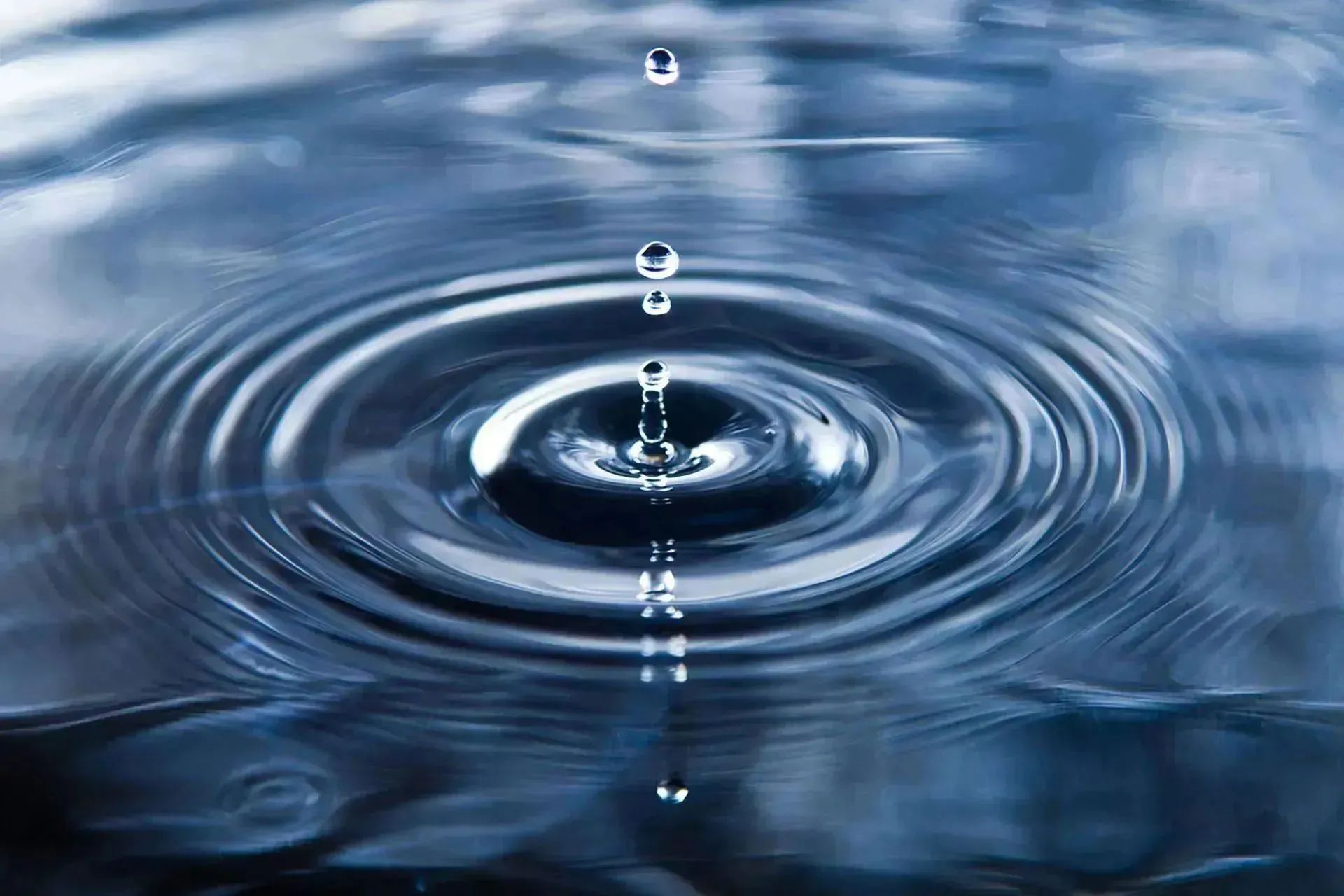 Water droplet creating ripples on a calm surface