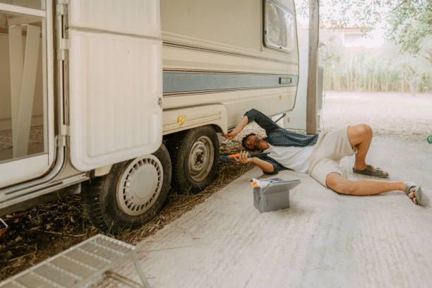 A Man Is Laying On The Ground Next To A Camper — Transtate Trailers & 4wd In Belconnen, ACT