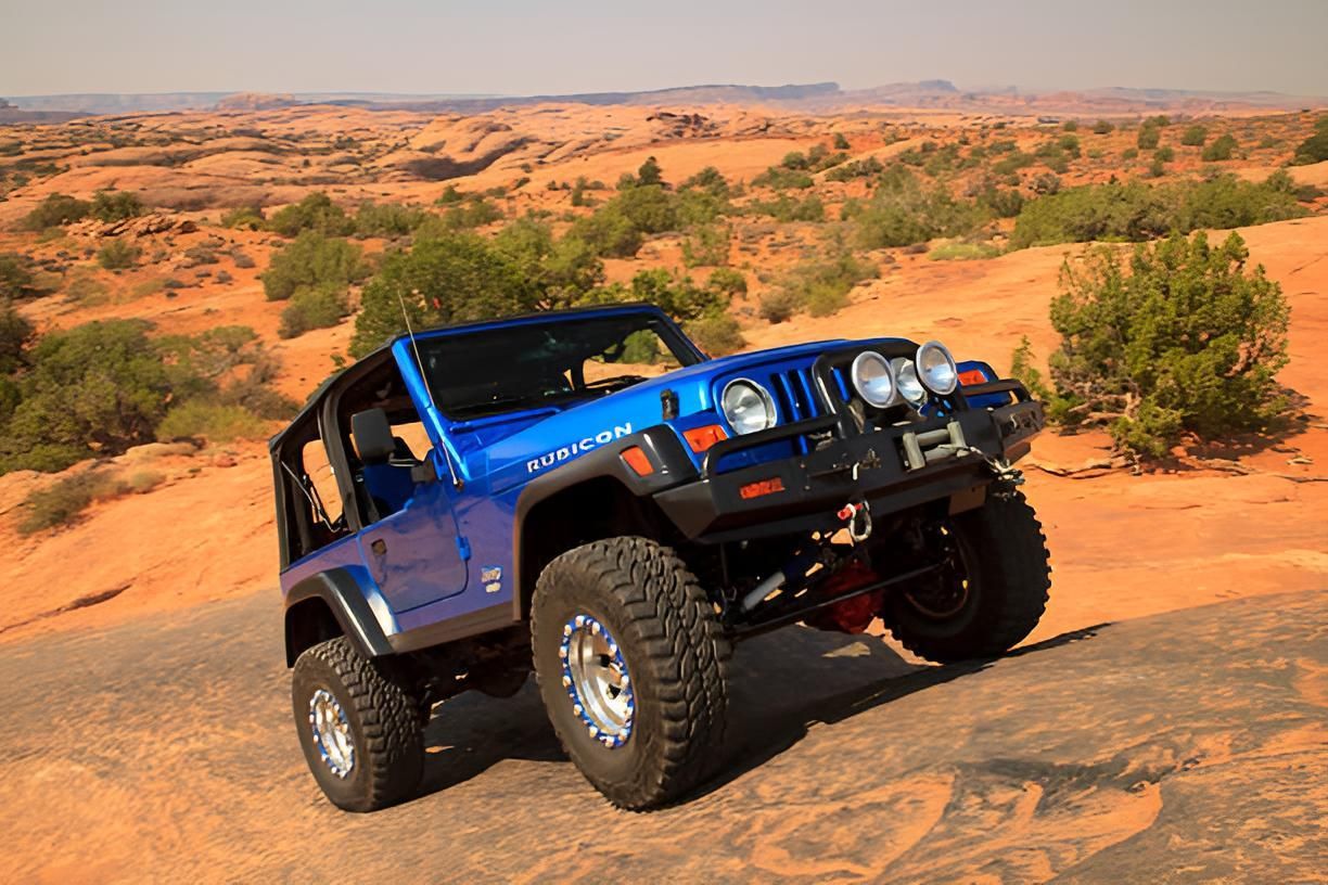 A Blue Jeep Is Driving Down A Dirt Road In The Desert — Transtate Trailers & 4wd In Belconnen, ACT