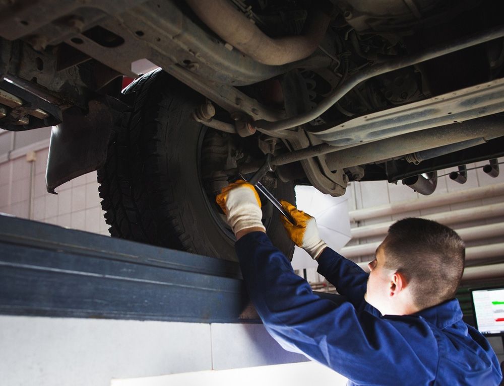 Mechanic in Blue Uniform, Using Wrench on Vehicle's Underside — Transtate Trailers & 4wd In Belconnen, ACT