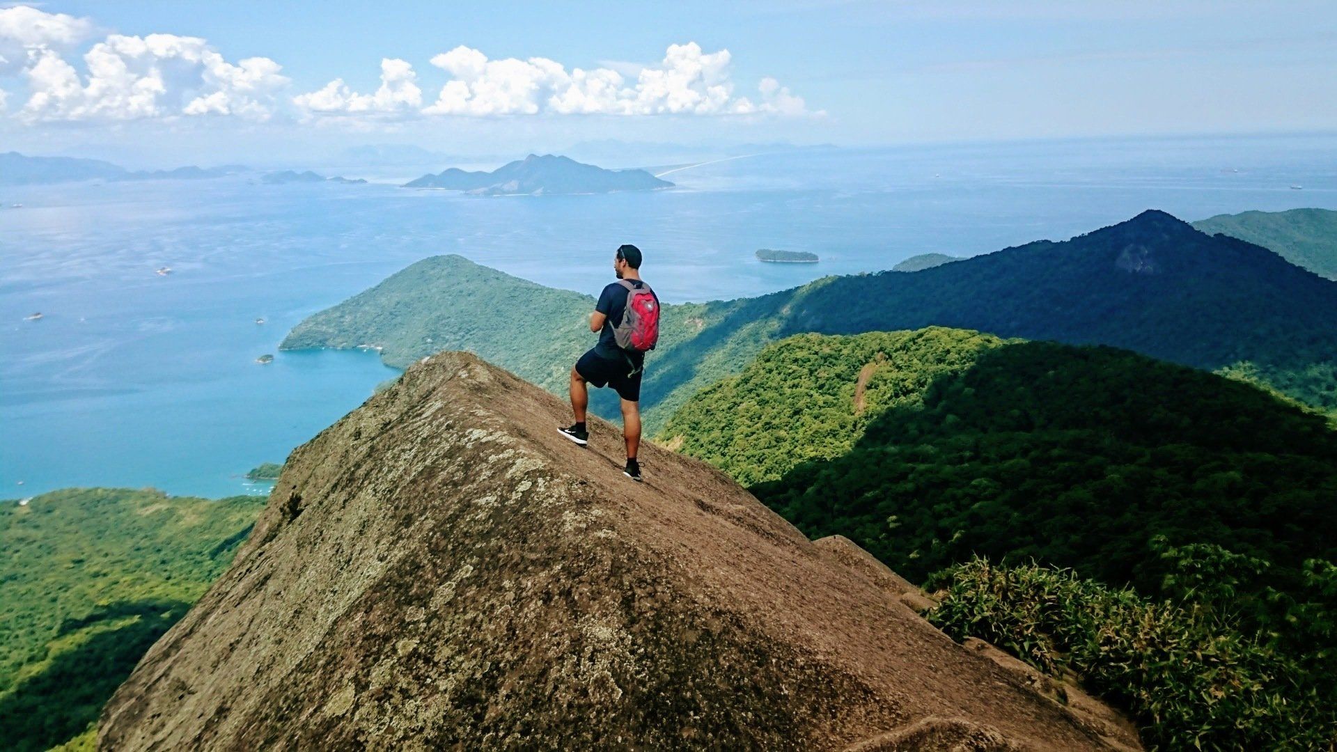 Pico do Papagaio - Ilha Grande, seen from above with an adventurer at the summit enjoying the view