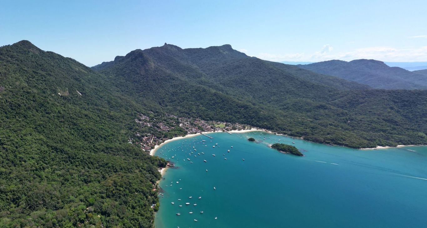 Aerial view of Vila do Abraão, Ilha Grande, with lush green mountains surrounding a turquoise bay 