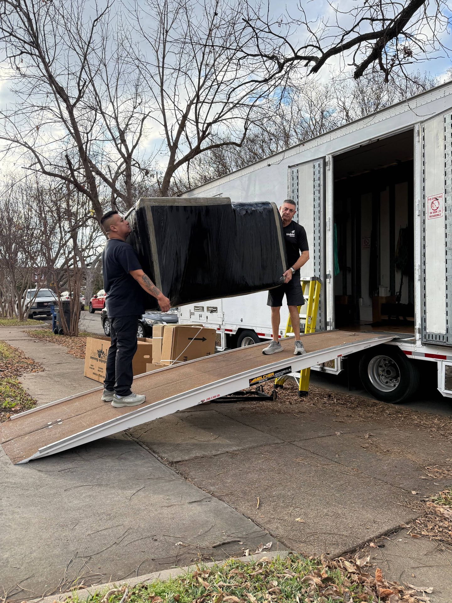 A man is moving a piano into a moving truck.