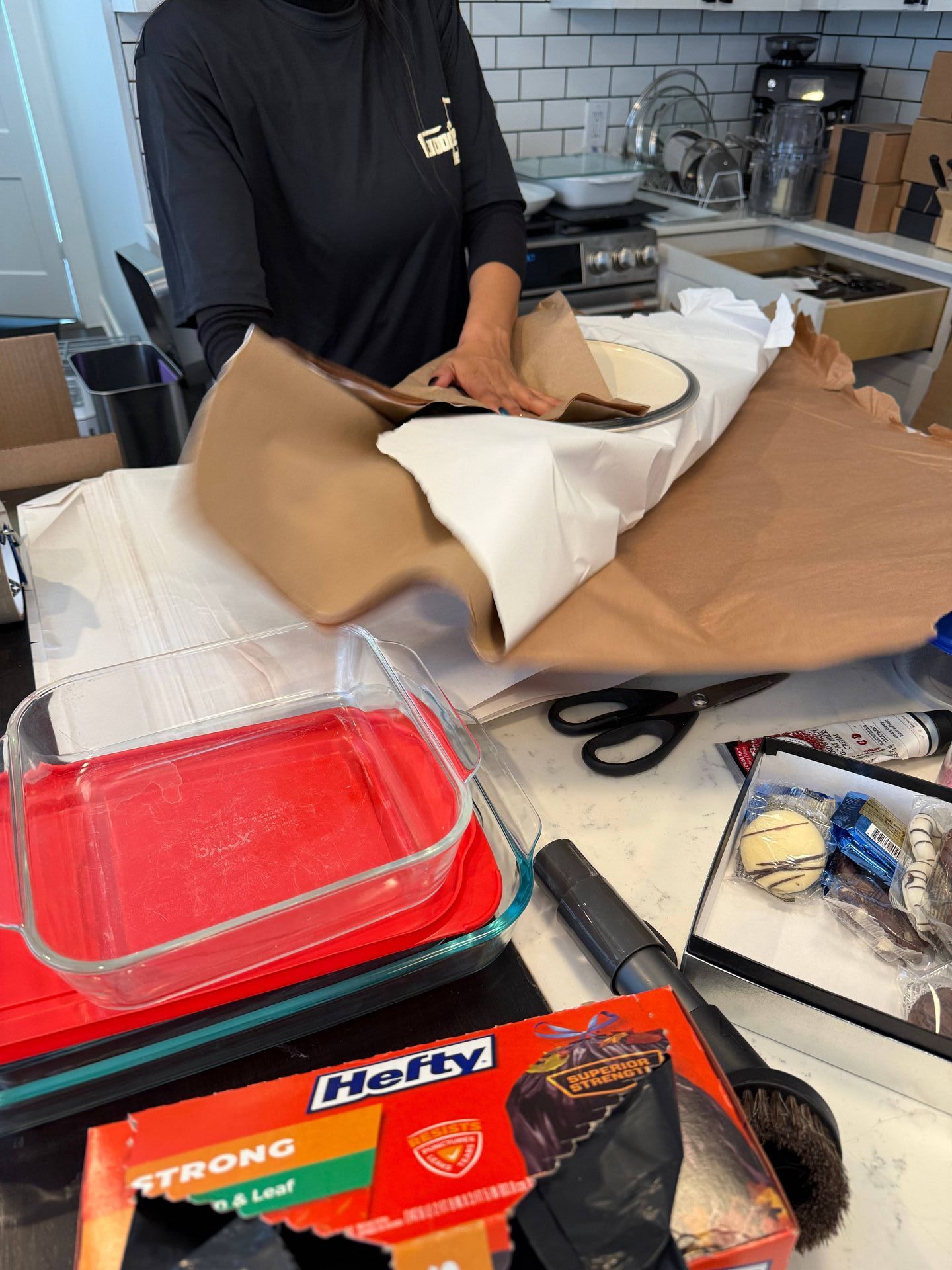 A person is wrapping a casserole dish with a box of hetty strong baking paper.