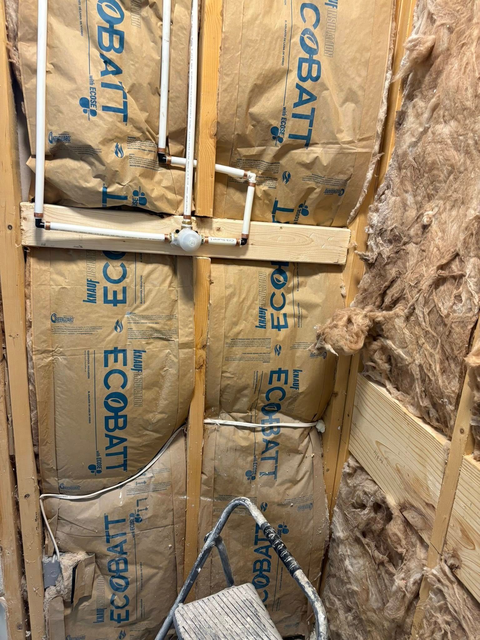 Under-sink view: stainless steel plumbing, two basins, trash can, cabinet door open.