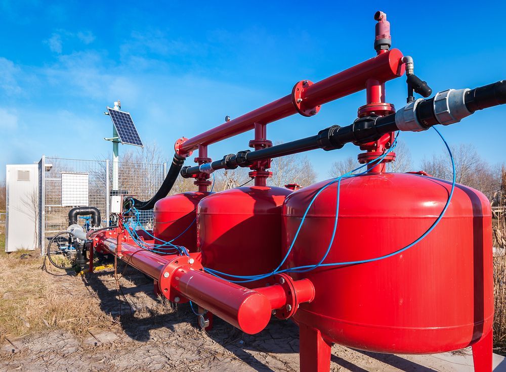 A Row of Red Tanks Sitting Next to Each Other in a Field — Sweeney's Pumps & Irrigation In Port Stephens, NSW