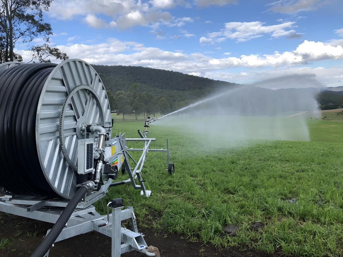 A Hose Reel is Spraying Water on a Grassy Field — Sweeney's Pumps & Irrigation In Medowie, NSW