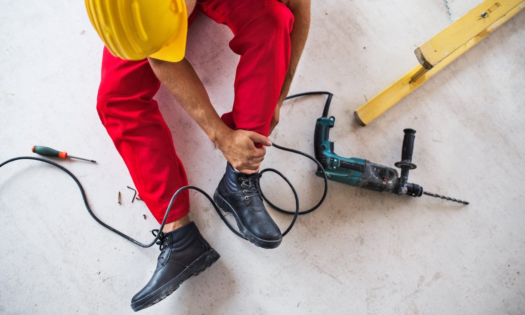 A man is sitting on the floor with a drill on the floor.
