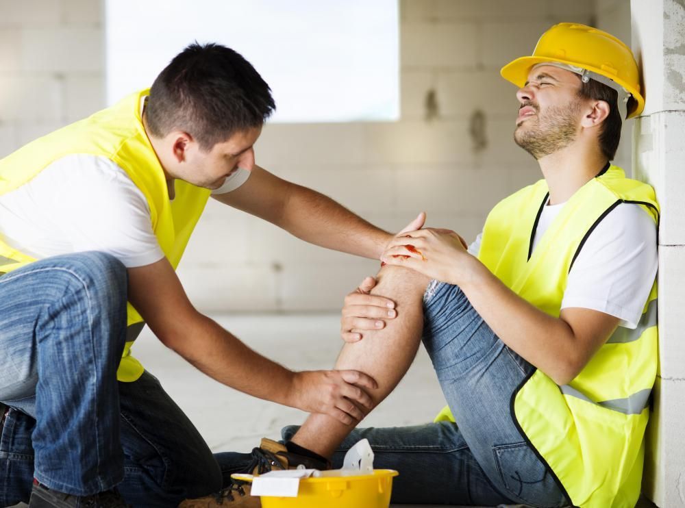 A man is helping another man who has a knee injury.