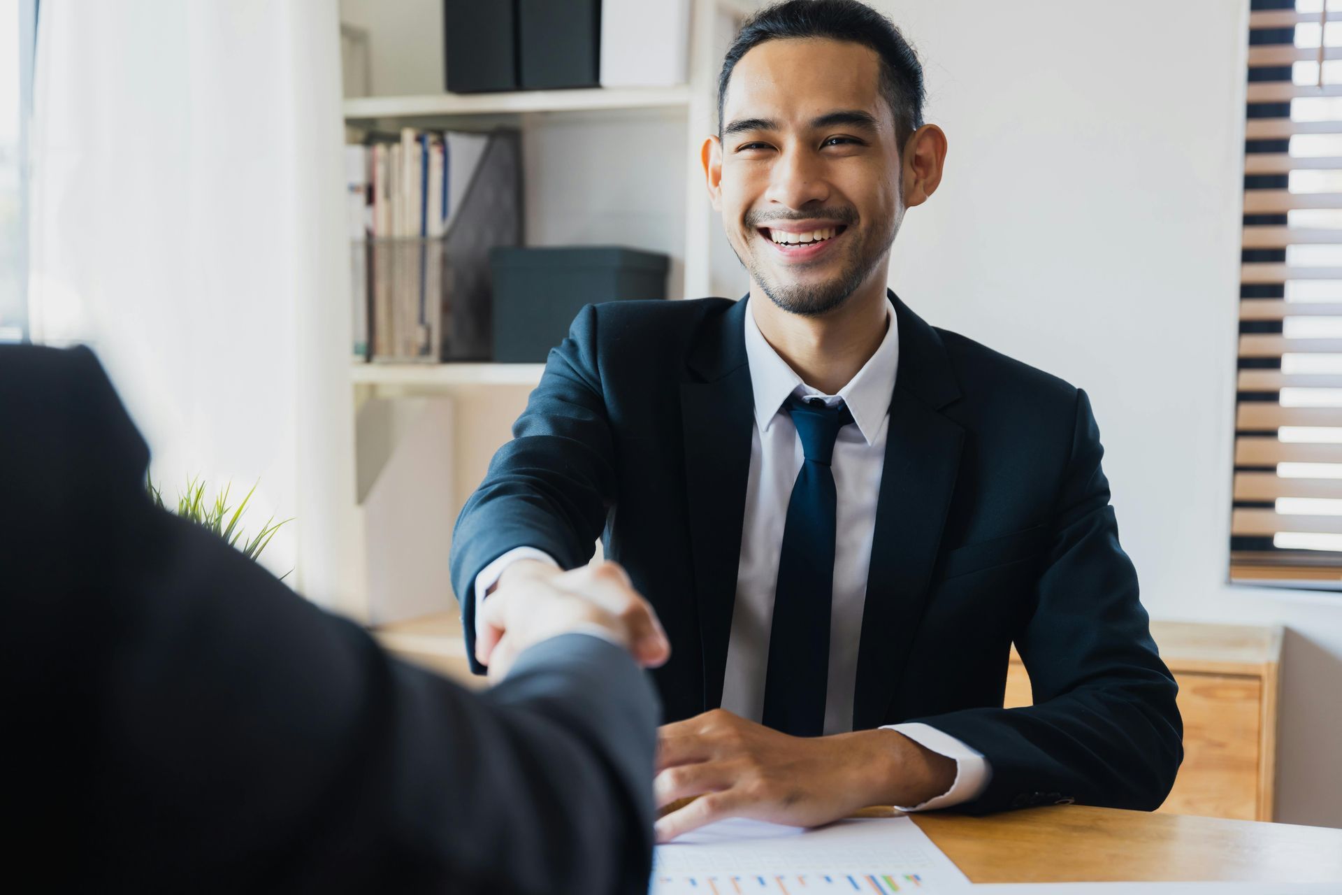 A man in a suit and tie is shaking hands with another man.