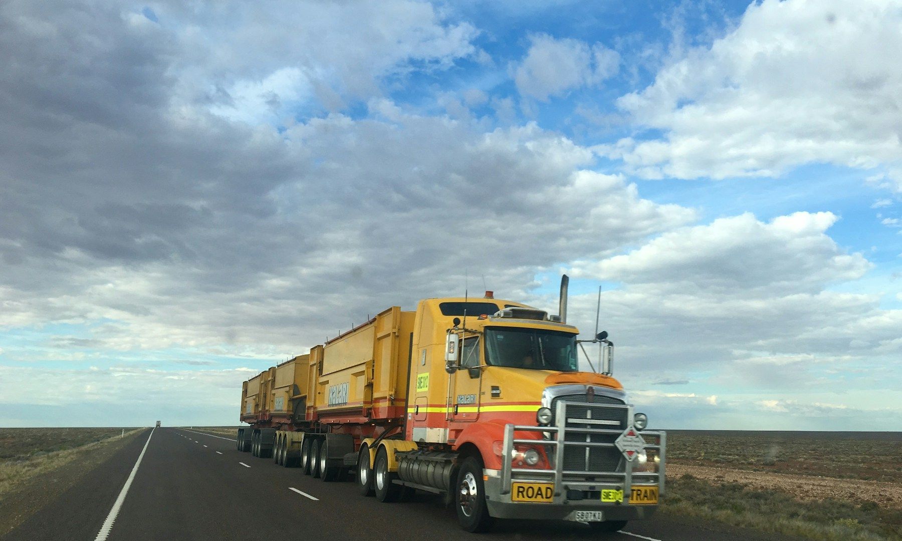A yellow and red semi truck is driving down a highway.