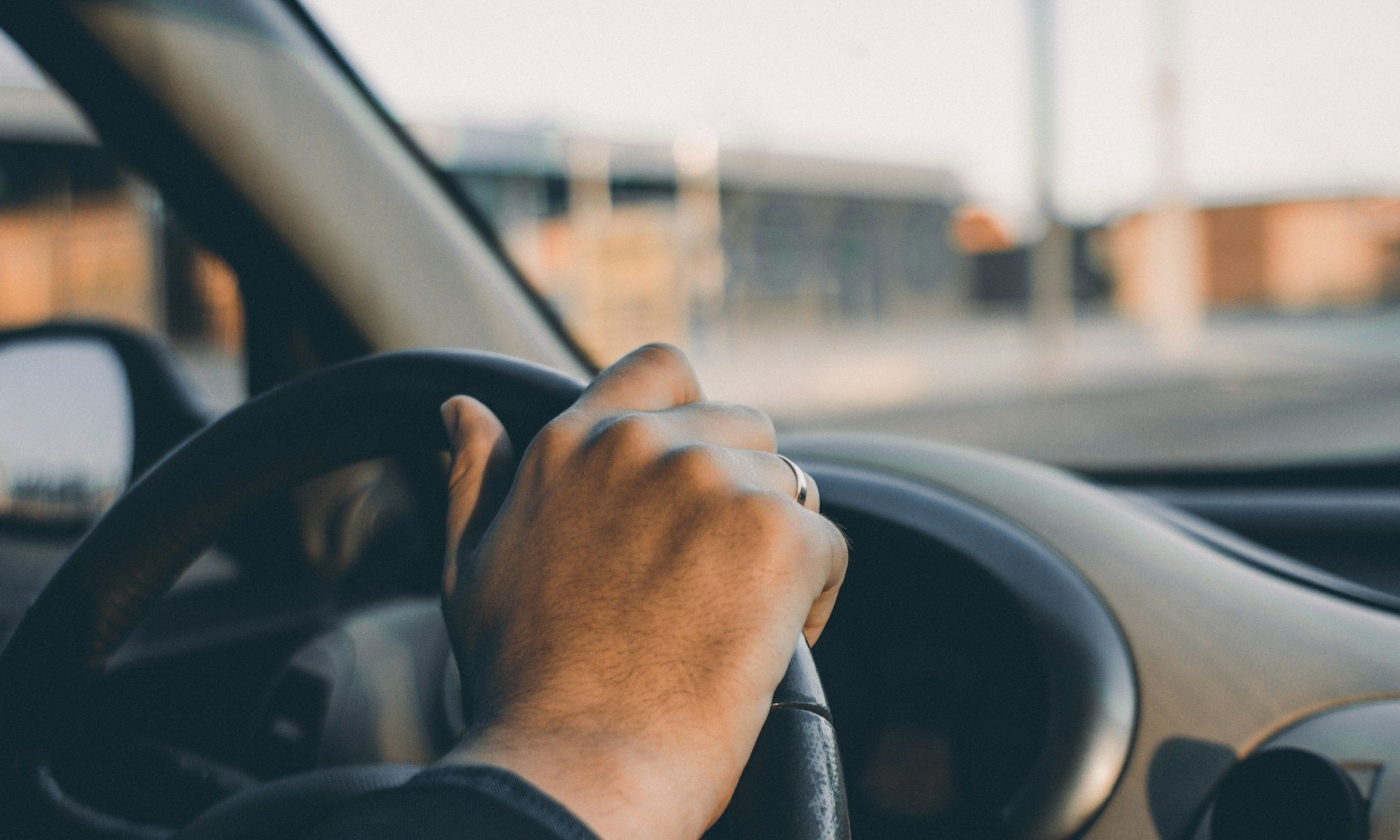 A close up of a person 's hand on the steering wheel of a car.