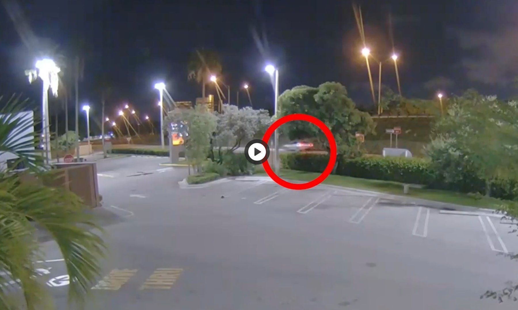 A car is parked in a parking lot at night.