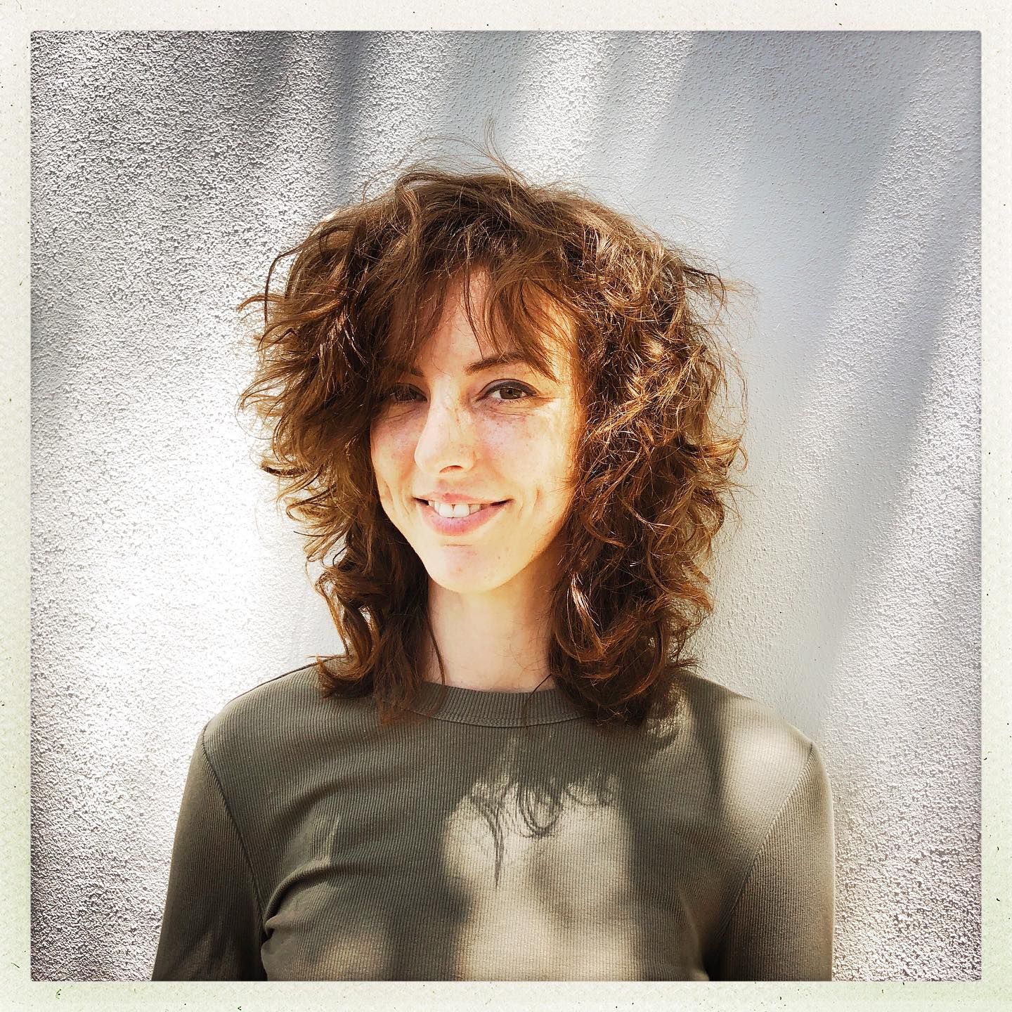 A woman with curly hair is smiling for the camera