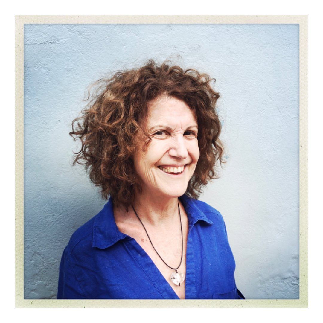 A woman with curly hair wearing a blue shirt and necklace