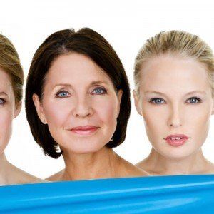 Three women are standing next to each other with a blue cloth between them