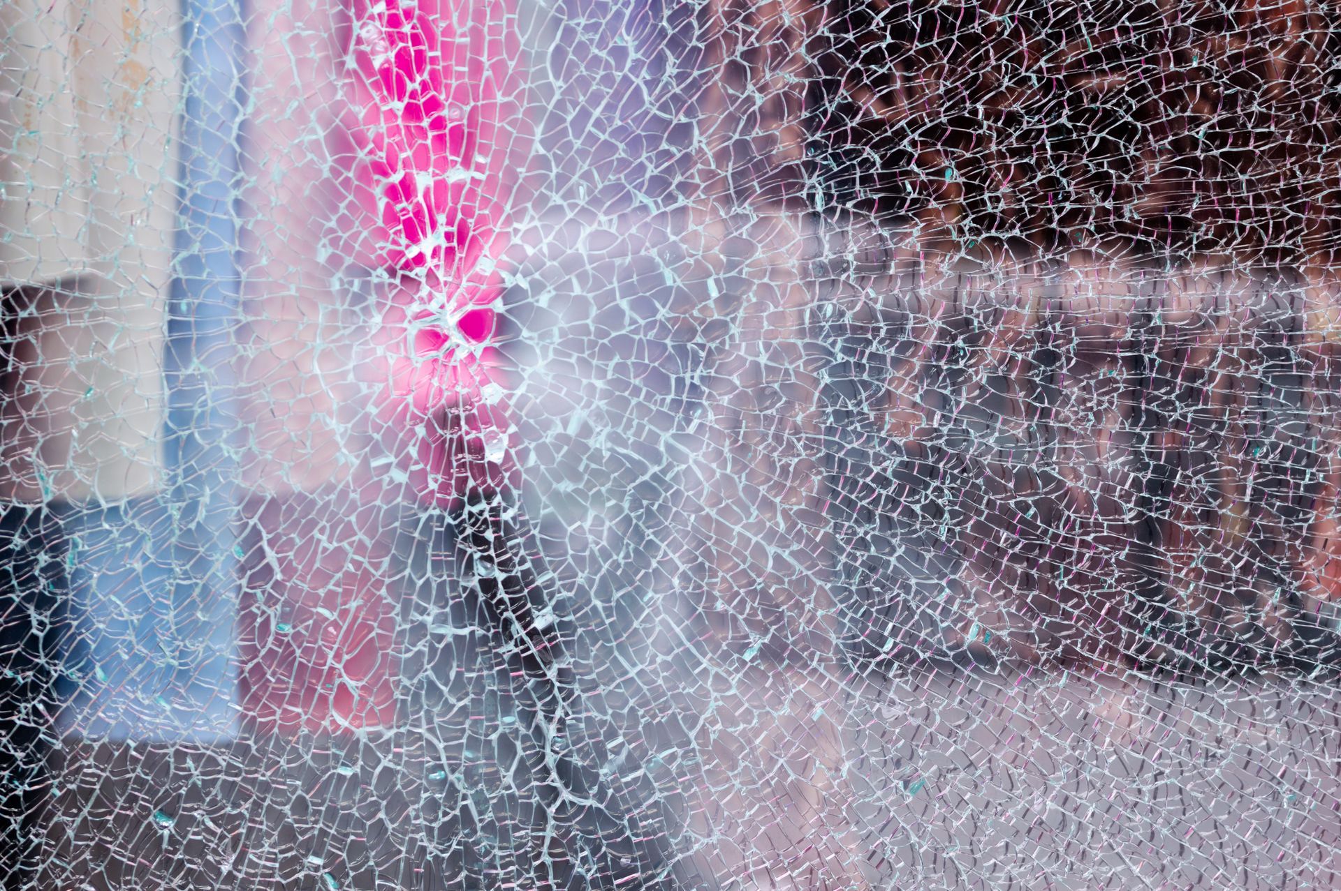 Broken glass of a shop window of a clothing store with unfocused background. Broken glass of a shop window of a clothing store with unfocused background.