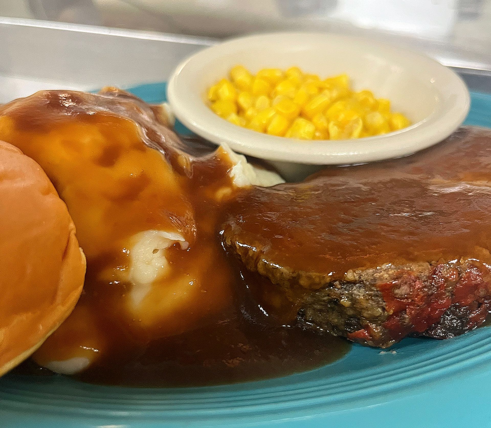 A plate of food with mashed potatoes , gravy and corn on the cob