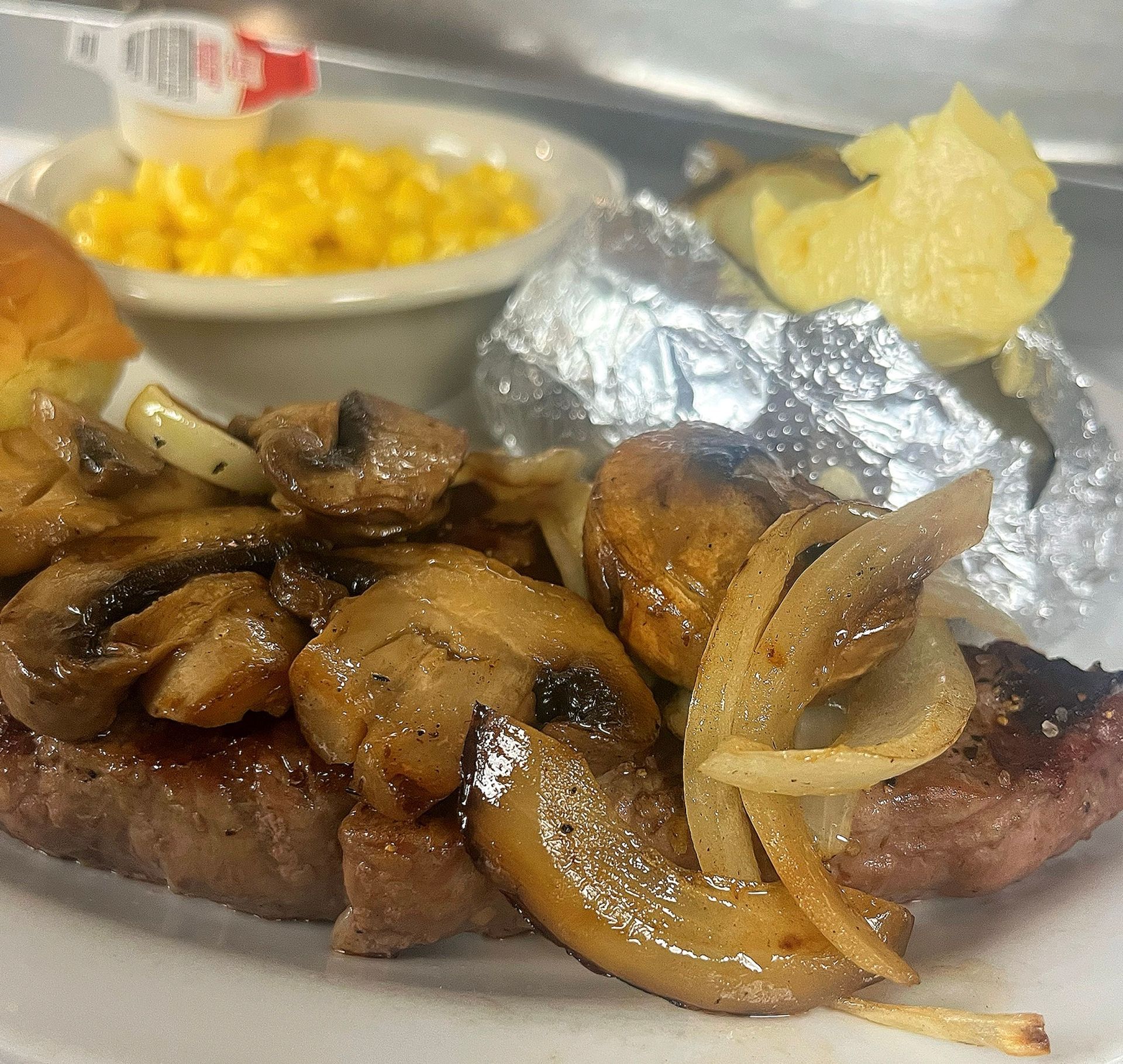 A plate of food with mushrooms onions and corn on the cob