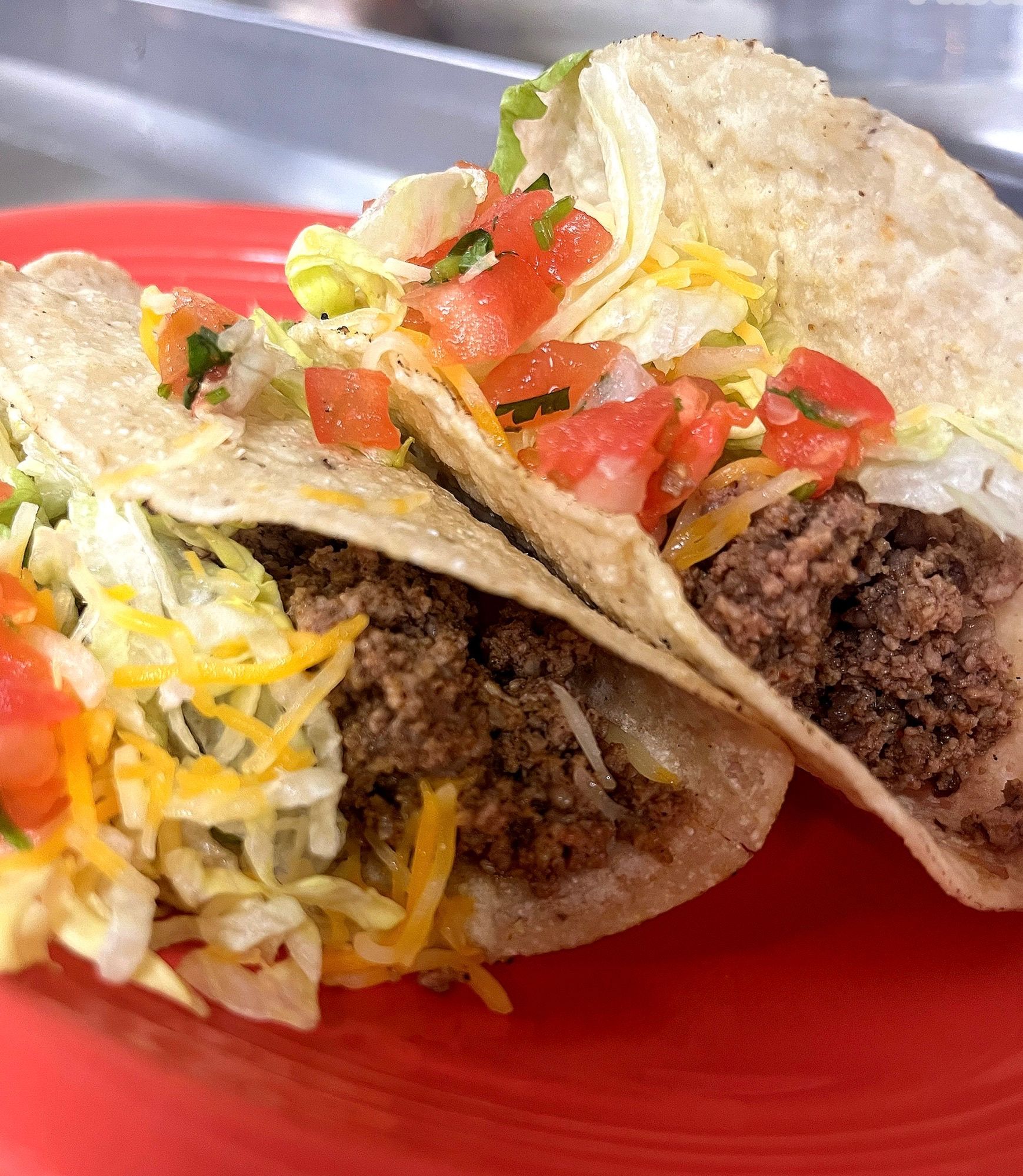 A close up of two tacos on a red plate