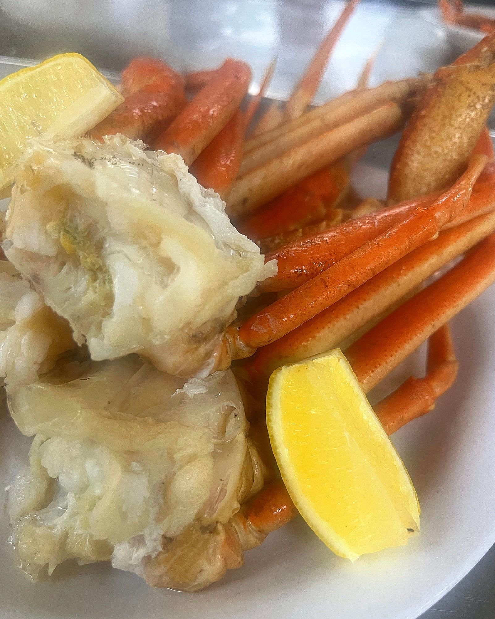 A close up of a plate of food with crab legs and lemon slices.