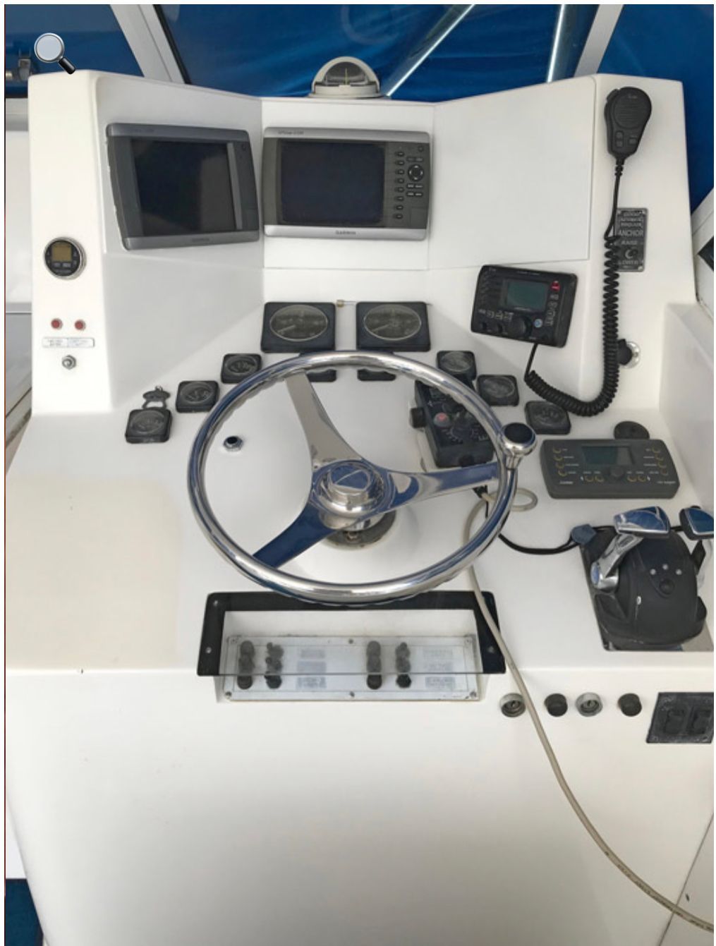 A white boat with a steering wheel and monitors