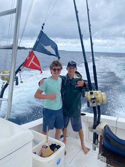 A man and a boy on a boat with fishing rods